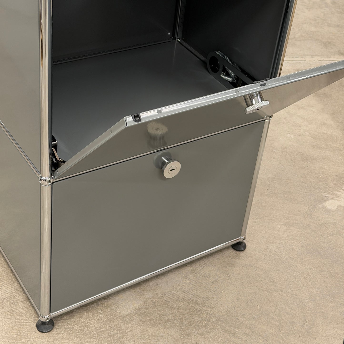 USM Haller Highboard 1x3 in mittelgrau mit zwei offenen Klappen und Chromgestell.
