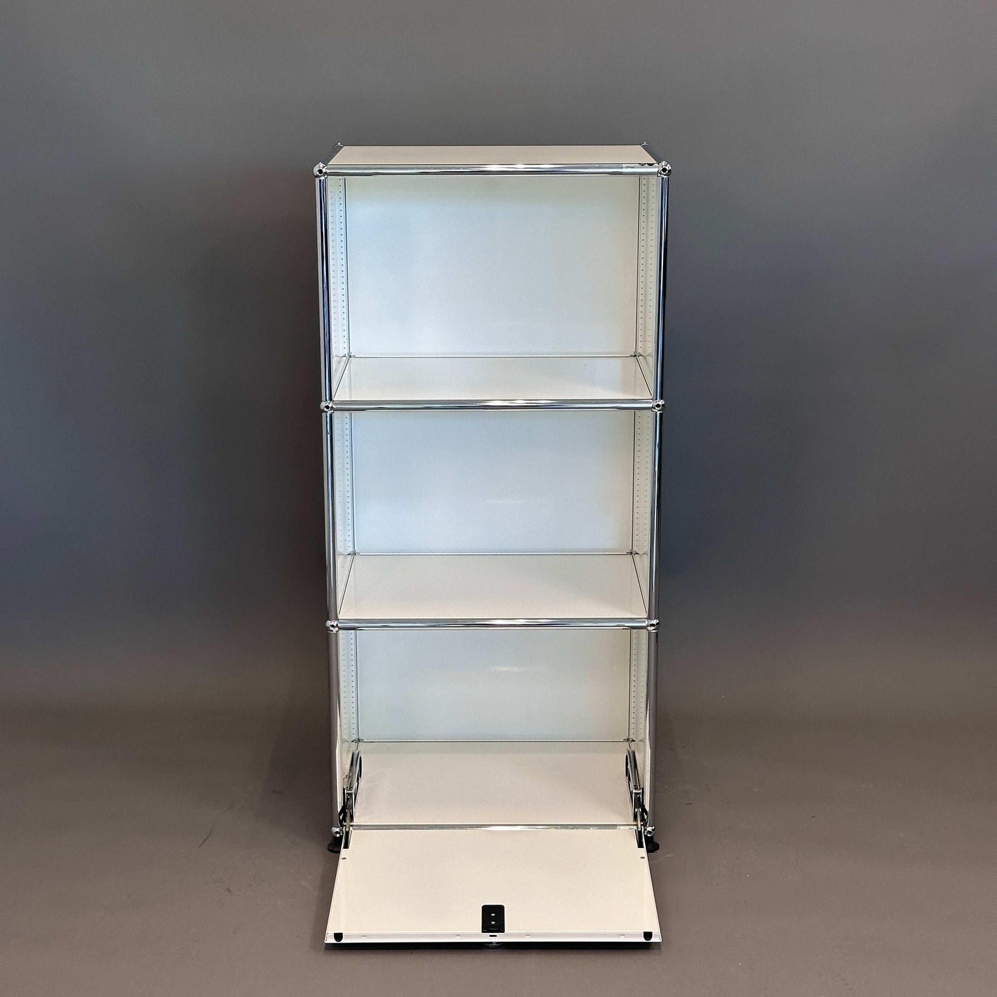 USM Haller Highboard 1x3 weiß mit geöffneter Klappe und drei Einlegeböden vor grauem Hintergrund