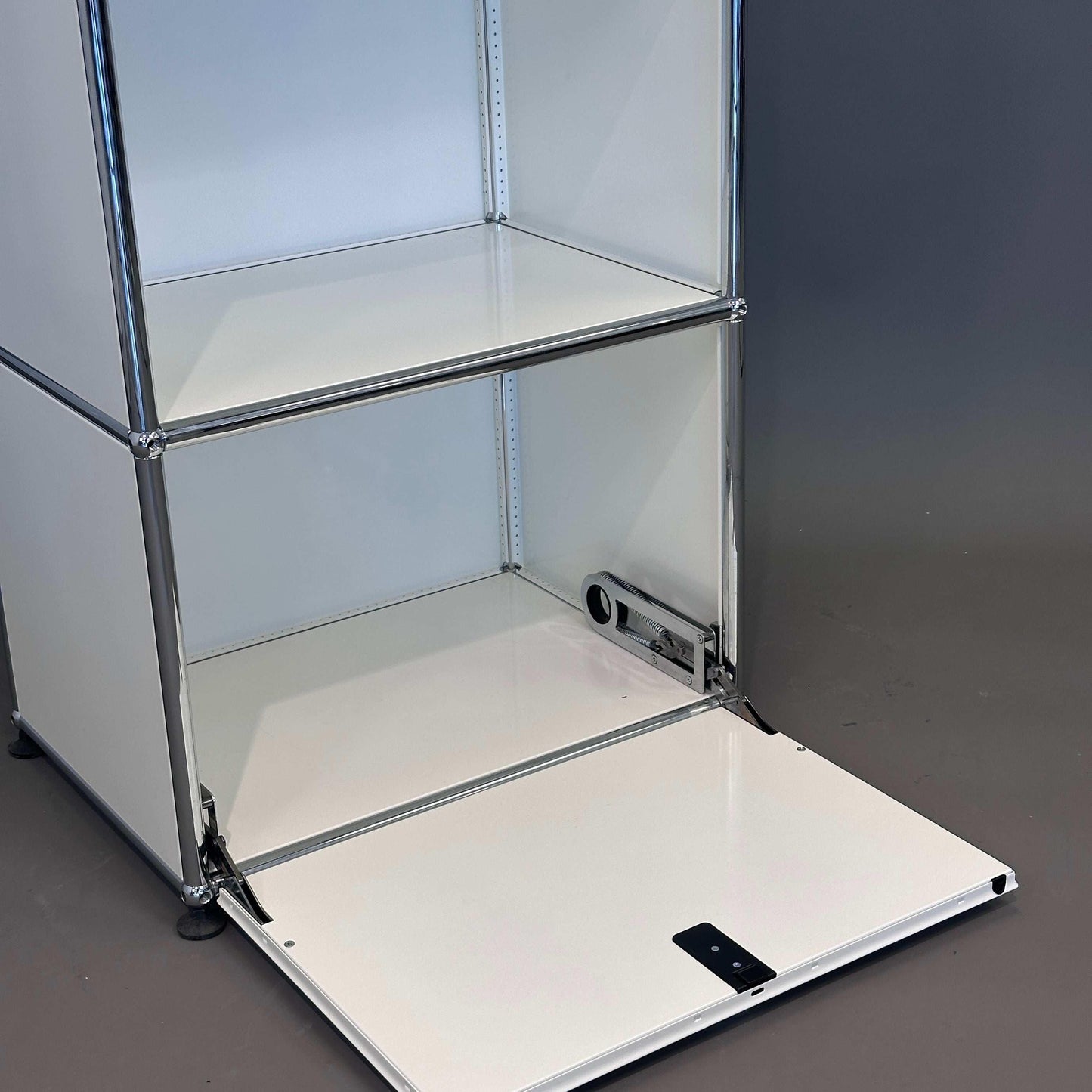 USM Haller Highboard 1x3 weiß mit geöffneter Klappe und chromfarbenem Gestell