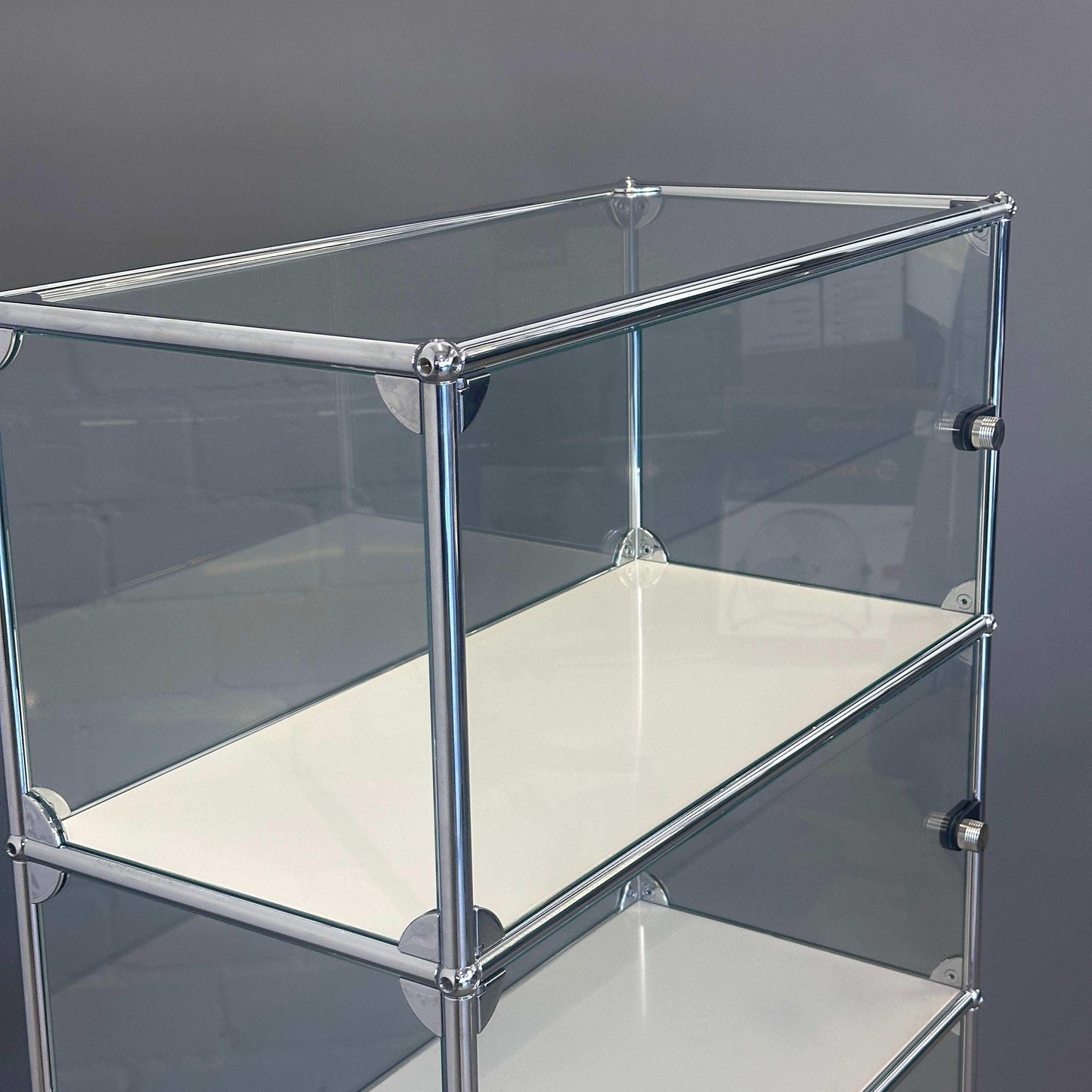 USM Haller Highboard Vitrine aus Glas mit weißen Fachböden und chromfarbenem Rahmen