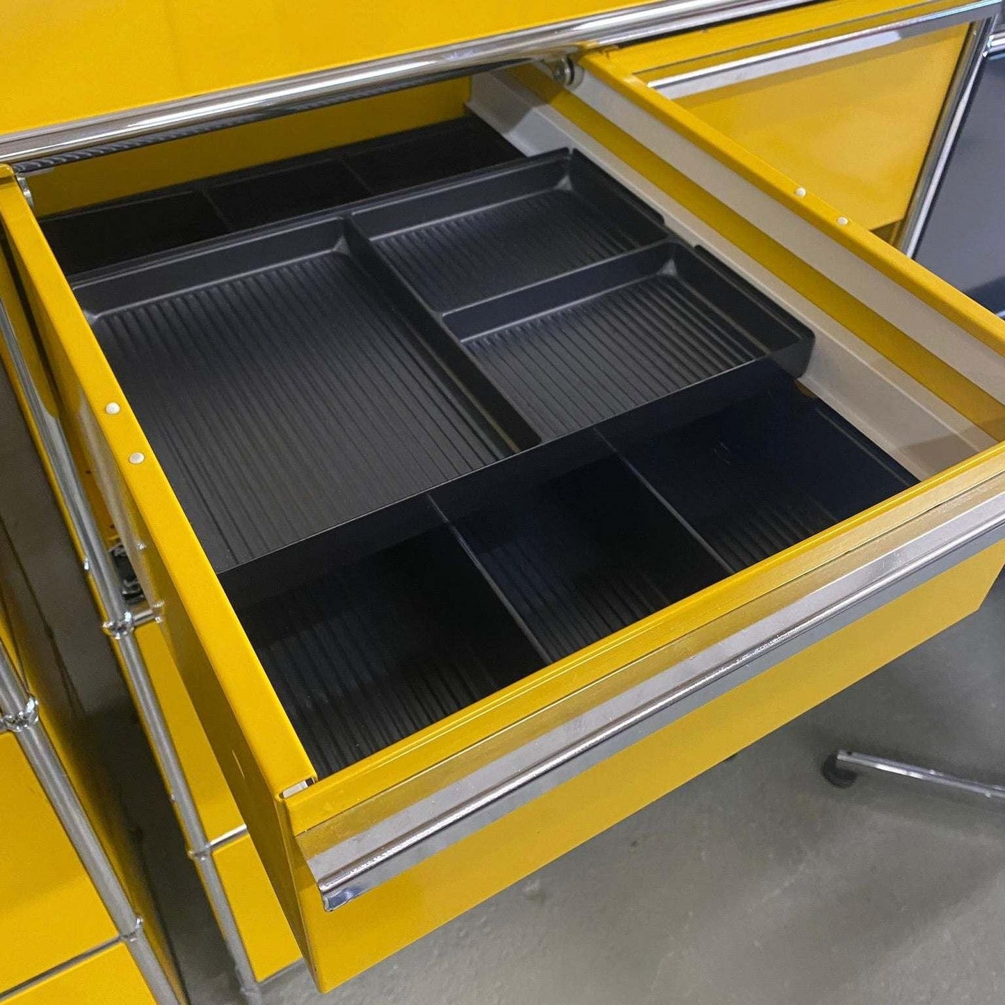 USM Haller highboard in gold yellow with open drawer showing black INOS drawer inserts and compartments