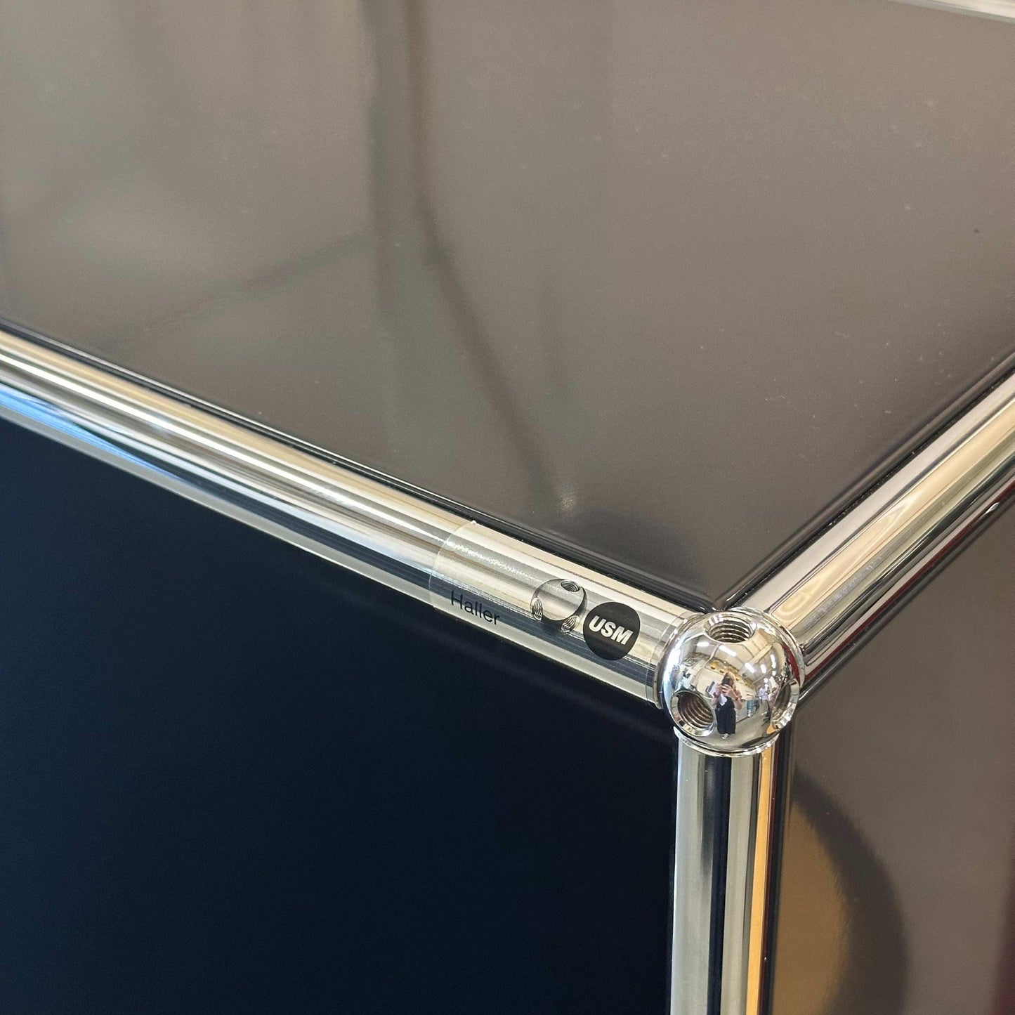Close-up of black USM Haller highboard corner with chrome frame and logo detailing