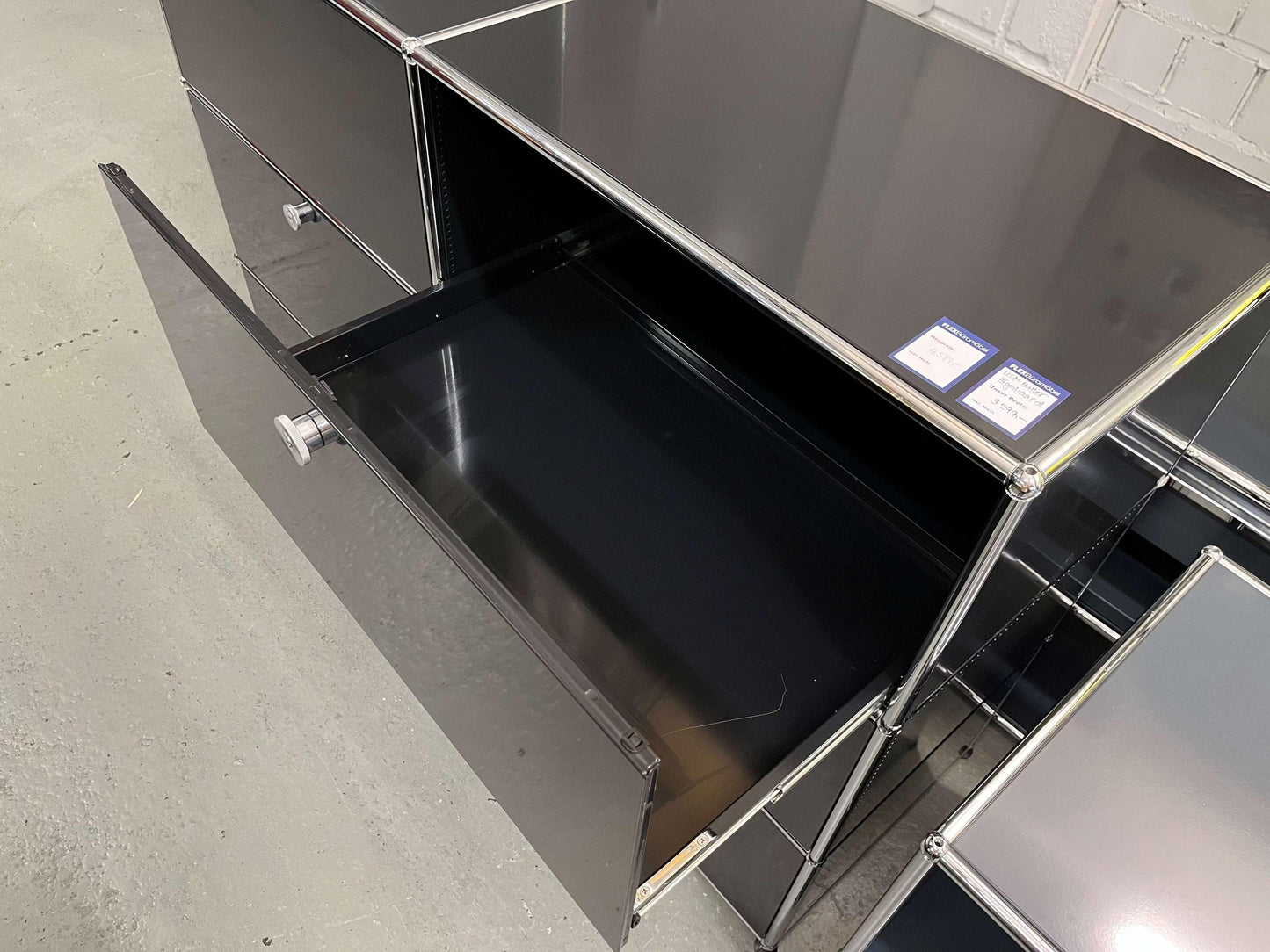 USM Haller Highboard in graphite black with open drawer and metal frame detailing