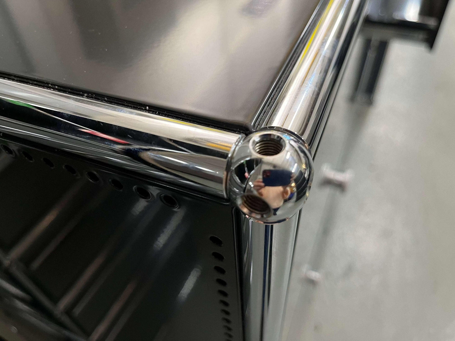 Close-up of chrome joint detail on a black USM Haller Highboard with metal frame and perforated panels