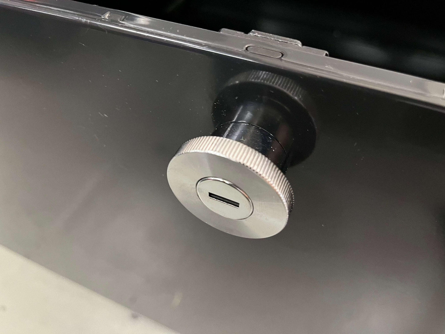 Close-up of the lock mechanism on the black USM Haller Highboard with metal knob and key slot.