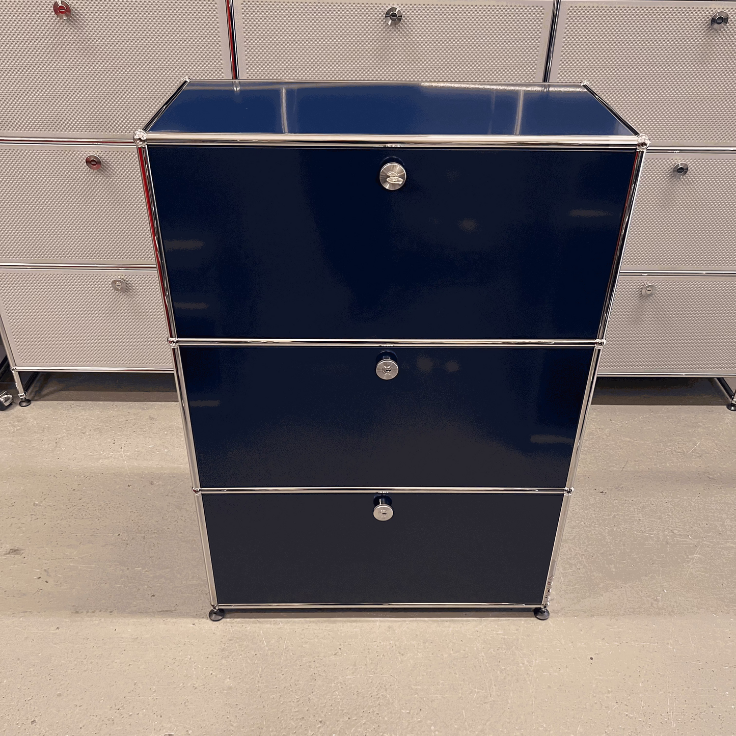 USM Haller highboard in steel blue with three flap compartments and chrome frame, dimensions 109x78x38 cm.