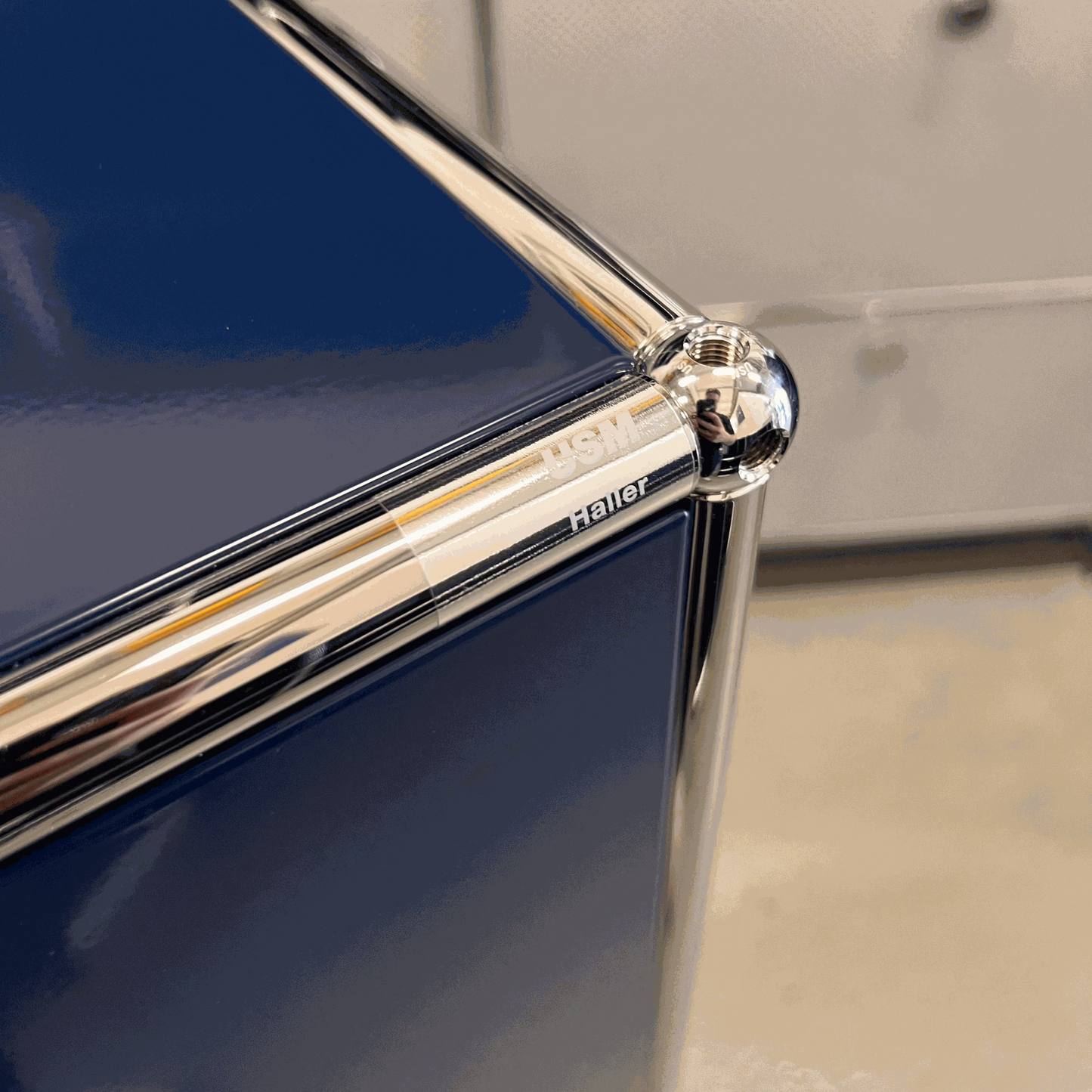 Close-up of USM Haller highboard corner in steel blue with chrome frame detailing and logo engraving