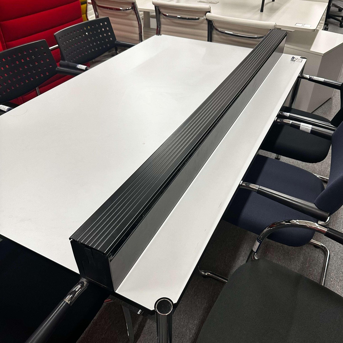 USM Haller Kabelkanal mounted on the side of a white office table organizing cables