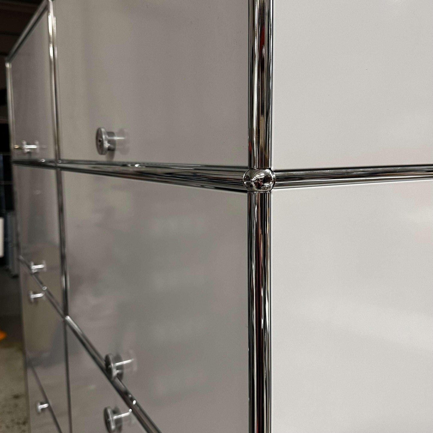 Close-up of the USM Haller Regal light gray steel cabinet with chrome frame and handles