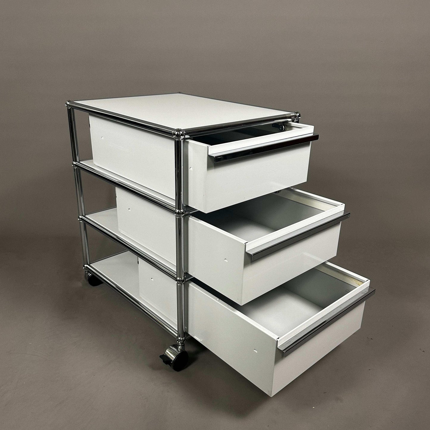 USM Haller light grey rollcontainer with three open drawers and chrome frame on wheels