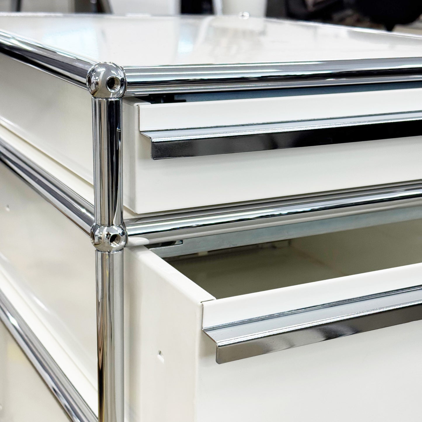 USM Haller Rollcontainer in Reinweiß mit drei Auszügen und Chromgestell, ein Auszug geöffnet.