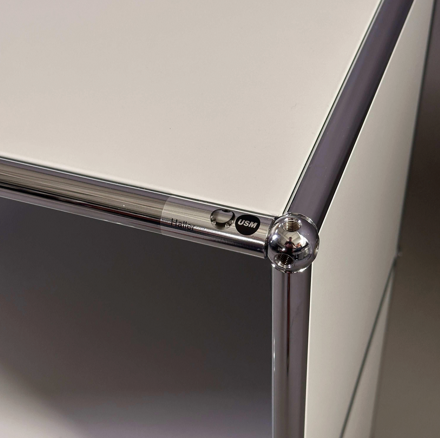 Close-up of light grey USM Haller Sideboard corner with chrome frame and logo detailing