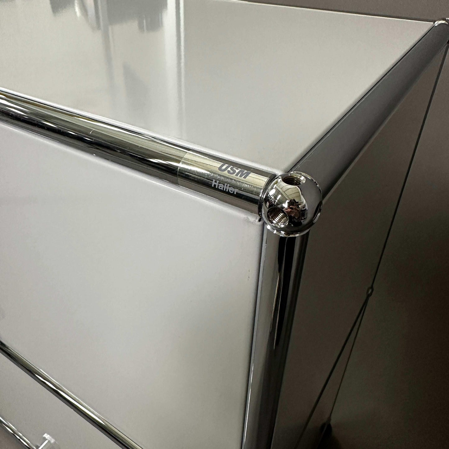 USM Haller light grey sideboard corner with chrome frame and logo close-up