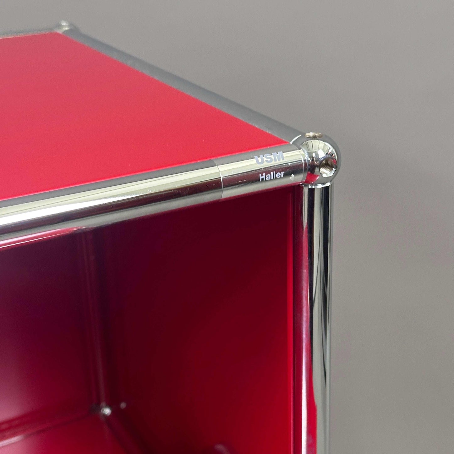 USM Haller Sideboard in Rubinrot mit zwei Klappen und chromfarbenem Rahmen, Modell 1x2, Nahaufnahme der Ecke und Marke