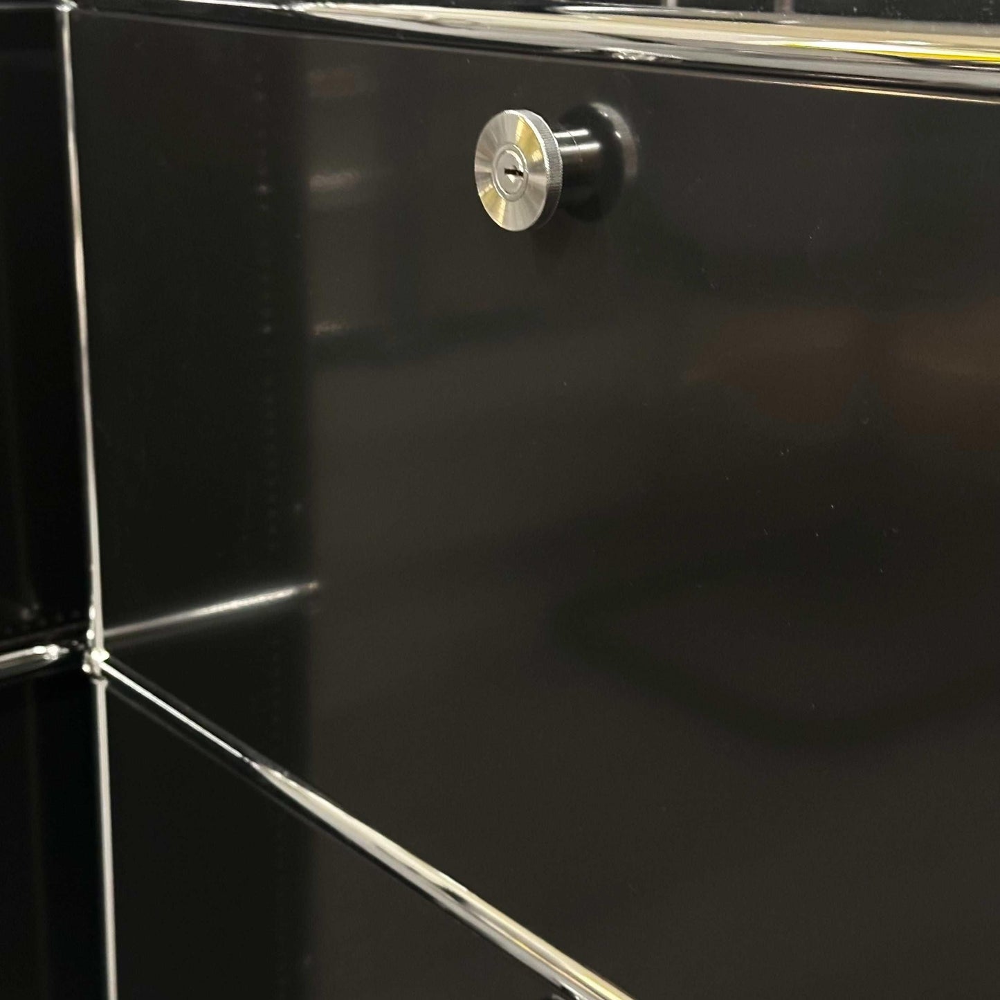 Close-up of graphitic black USM Haller Sideboard corner with metal locking knob and chrome frame detailing