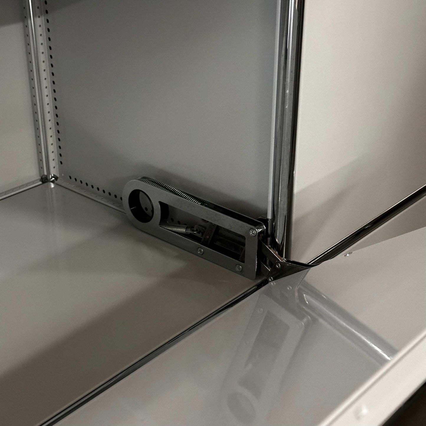 Close-up of locking mechanism inside light gray USM Haller Sideboard with metal shelves and frame