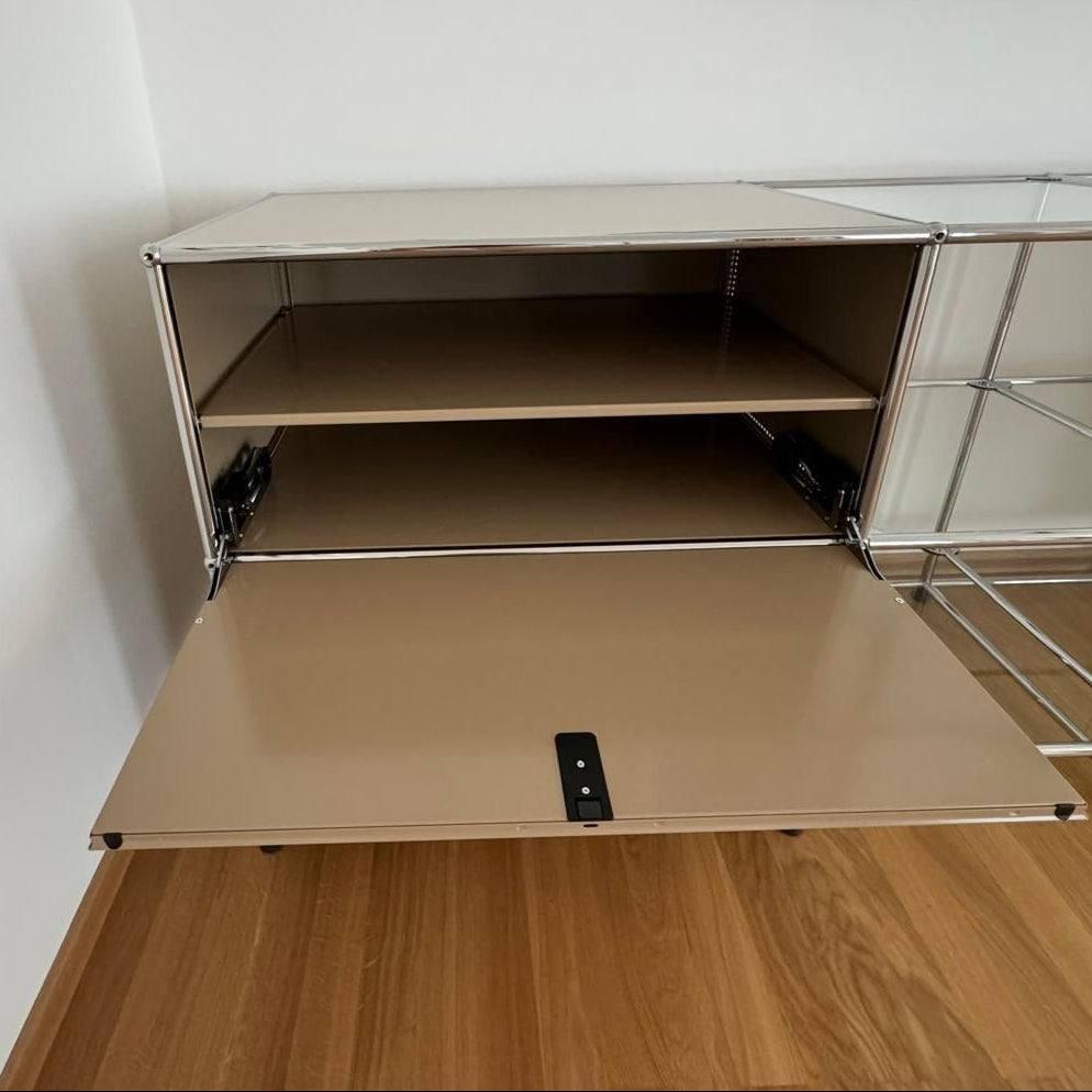 USM Haller Sideboard 5x2 beige weiß mit geöffnetem Klappfach und Glasdetails auf Holzboden