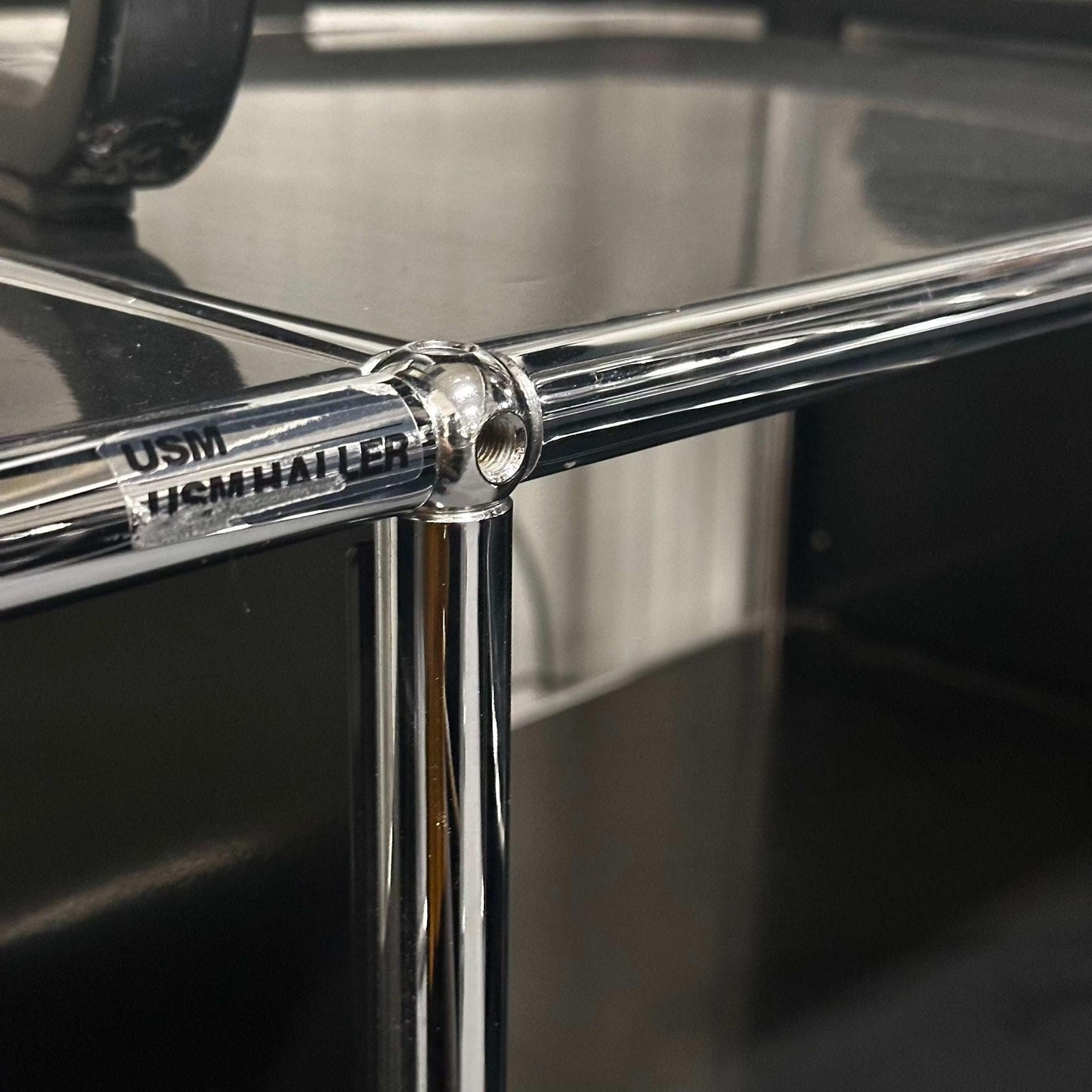 Close-up of the chrome joint detail on a black USM Haller Sideboard with 2x2 open compartments, measuring 152x74x52 cm