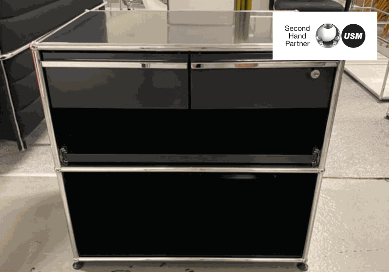 USM Haller Sideboard in graphite black with chrome frame, featuring drawers and a cabinet, modern and functional design.
