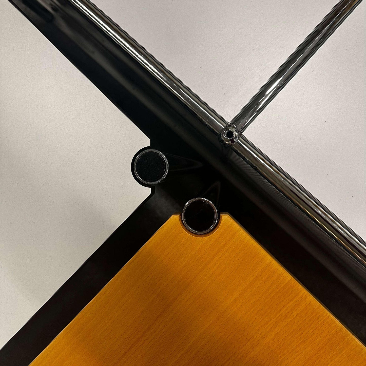 Close-up of USM Haller Tisch corner with chrome frame and beech wood tabletop
