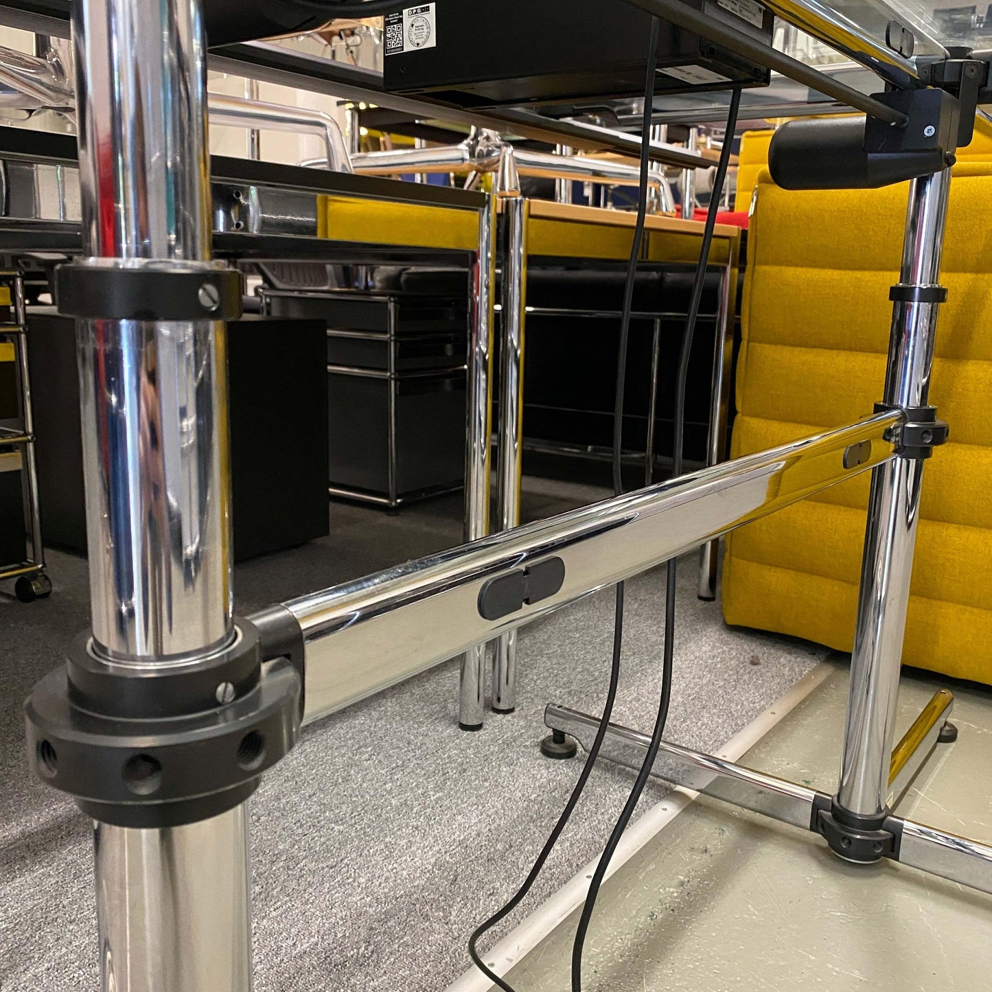 Close-up of the chrome frame and electric height adjustment mechanism of the USM Kitos 180x90cm glass tabletop desk