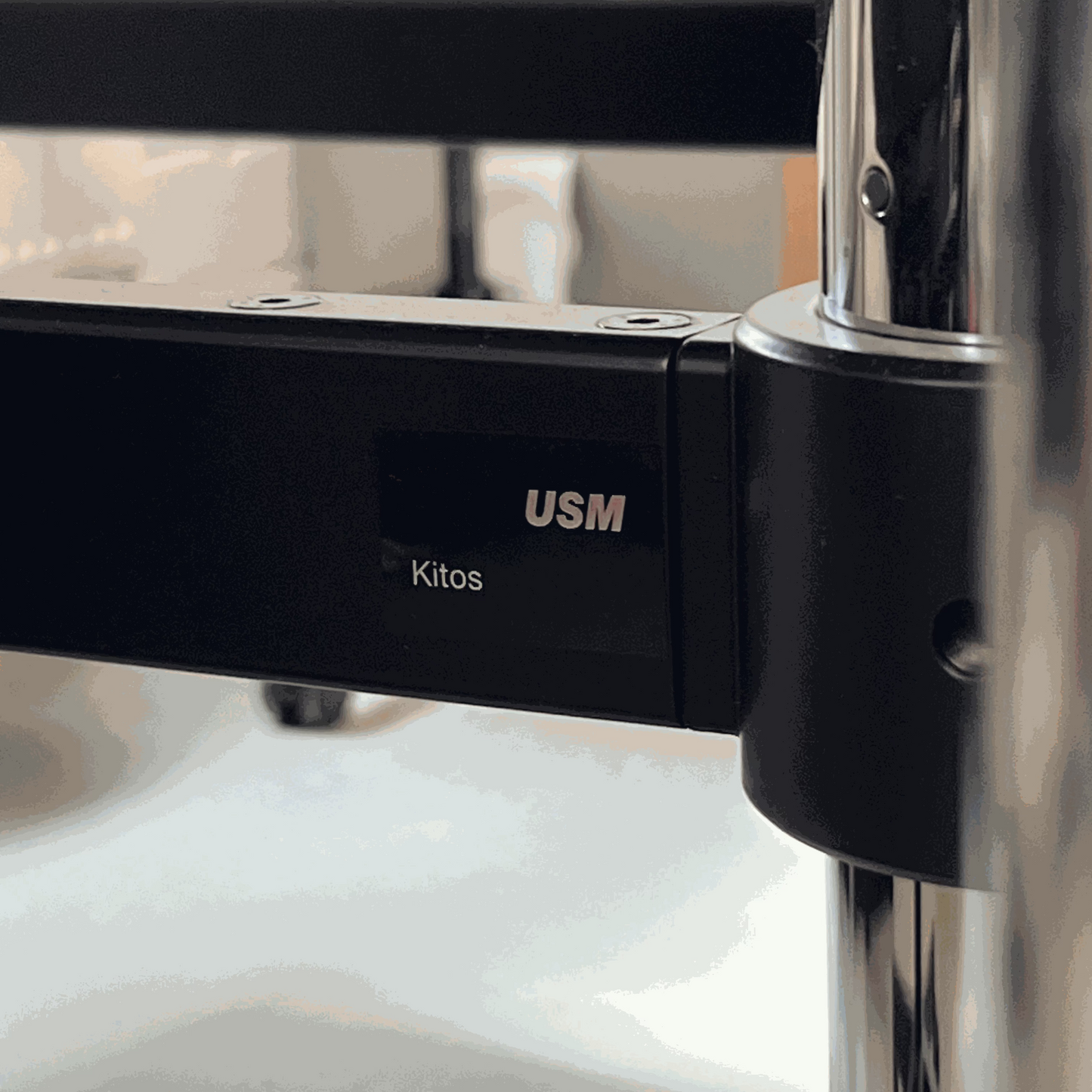 Close-up of USM Kitos E2 electric height-adjustable desk frame in black with logo and metal support details.