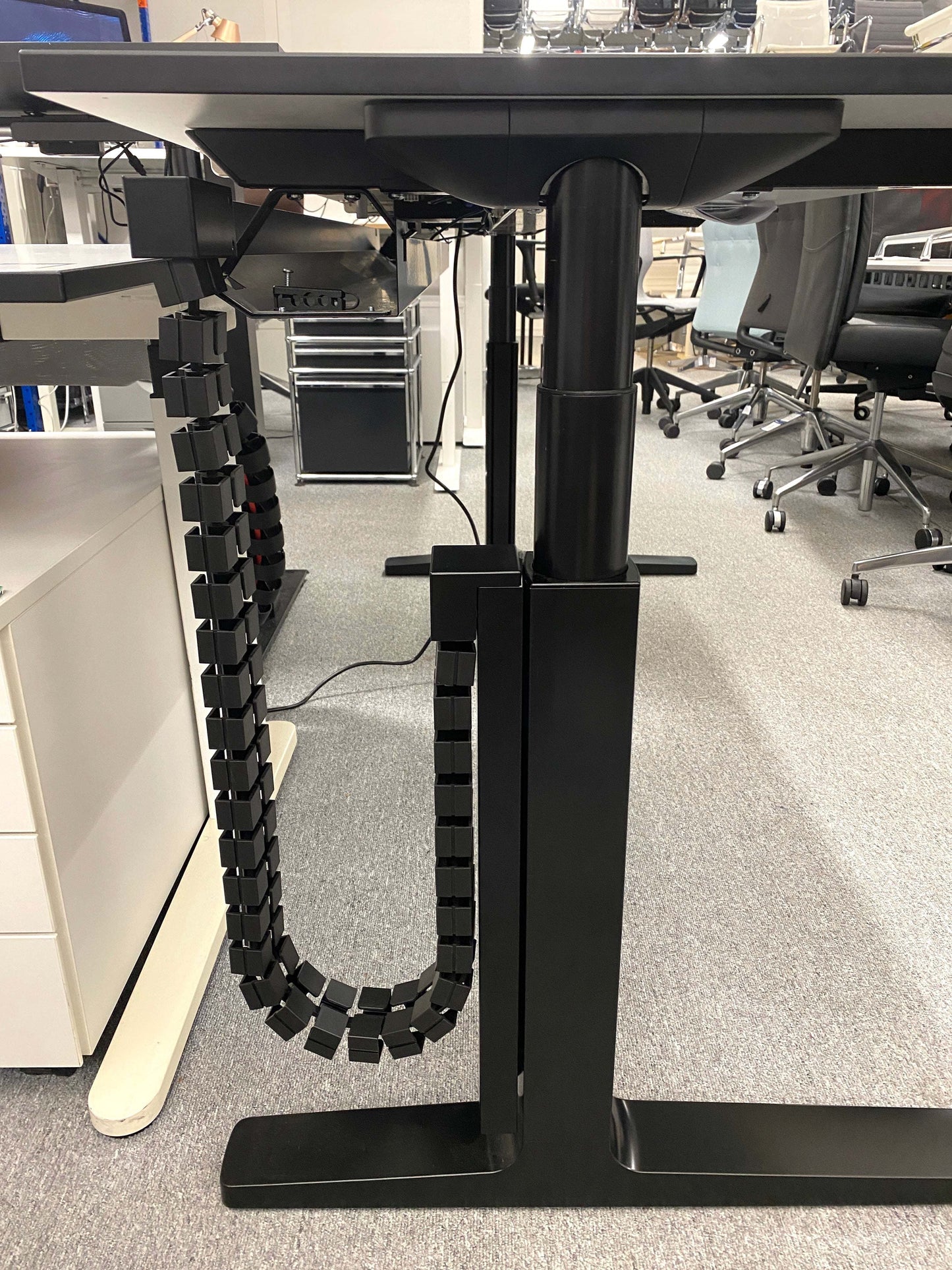 Vario Change 180x80cm electric height adjustable desk with black C-leg frame and cable management system in office setting
