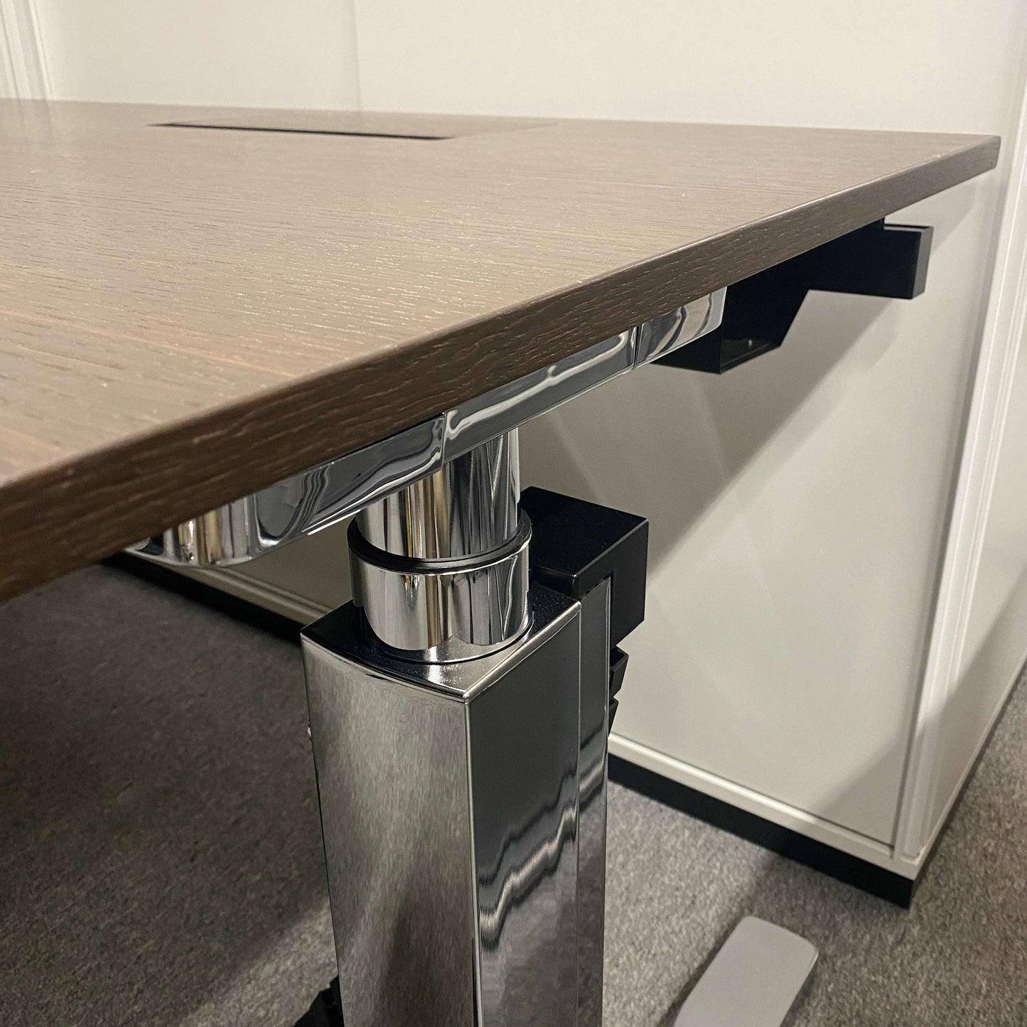 Close-up of Vario Change 200x100cm electric height-adjustable desk with smoked oak tabletop and chrome T-foot frame
