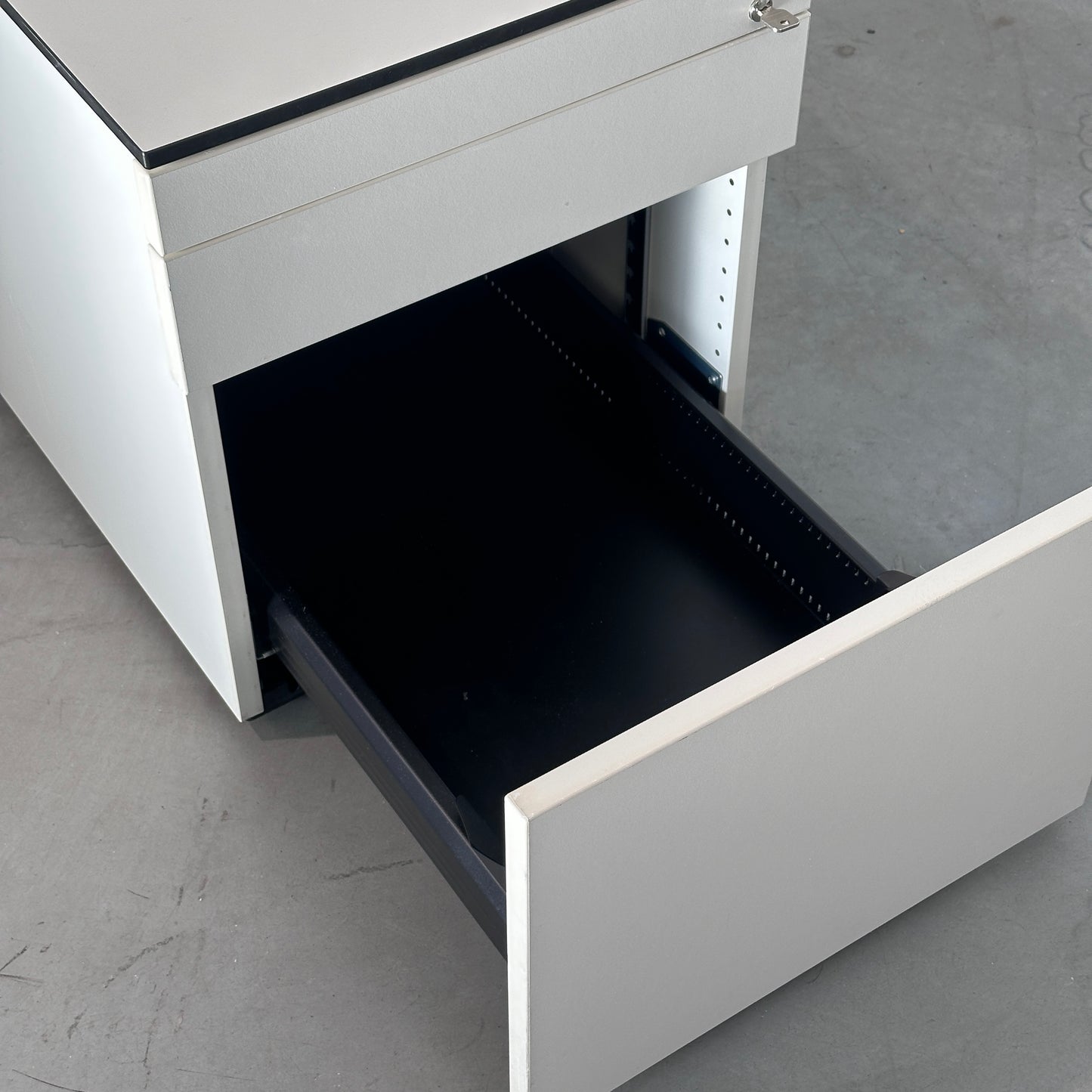 Weißer Vario Rollcontainer mit drei Schubladen, schwarzer Kante und offener Stiftschublade, Maße 44x51x80 cm.