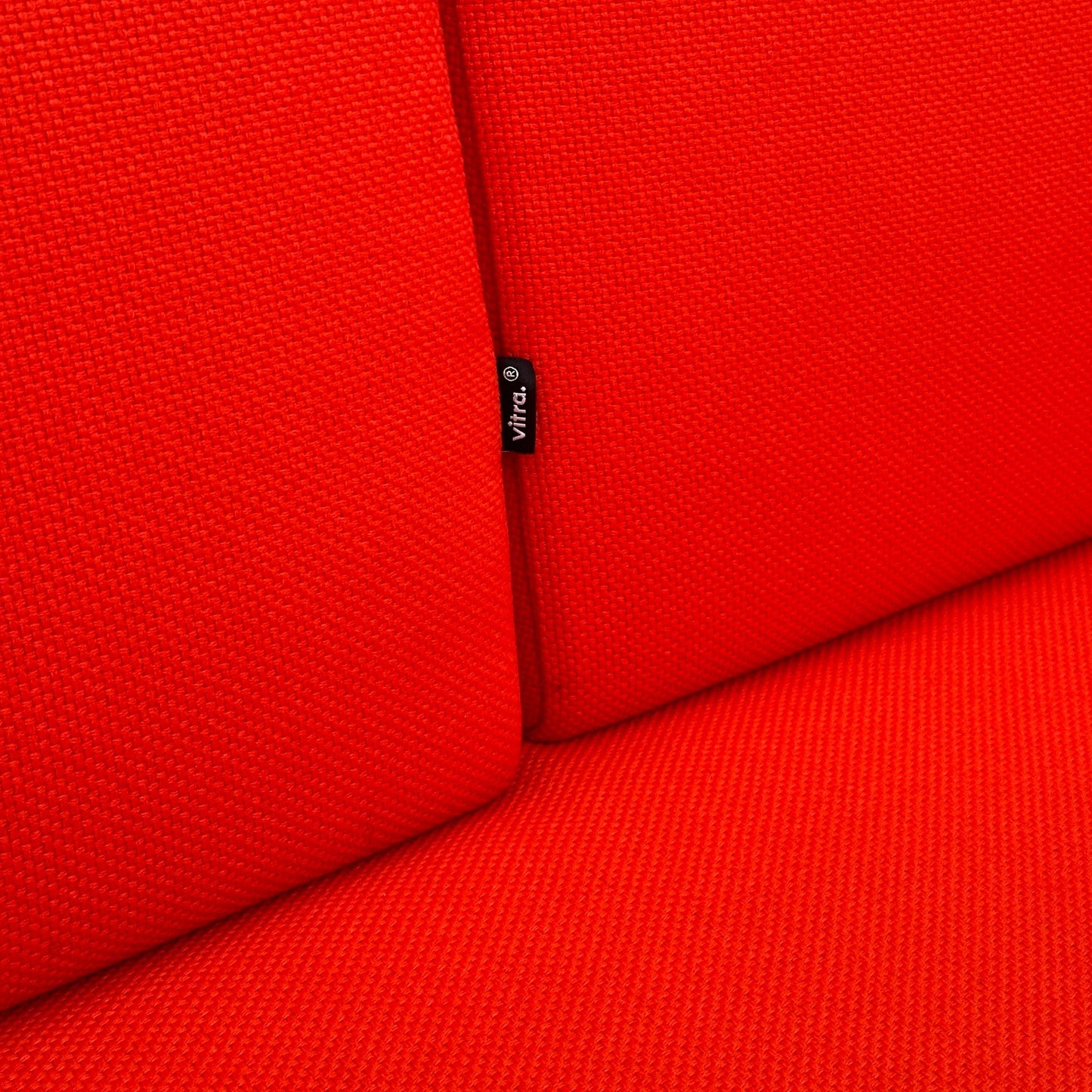 Vitra Alcove Cabin 2-Sitzer Highback in hellrotem, robustem Stoff mit feiner Struktur und Vitra-Label am Polster.