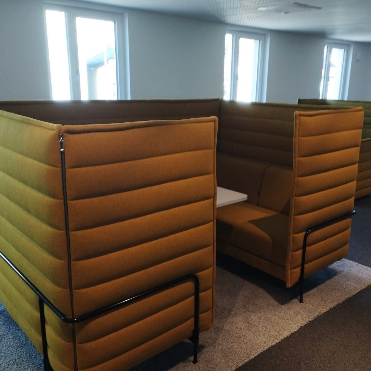Vitra Alcove Cabin highback seating with padded mustard upholstery and integrated white worktable in modern office setting