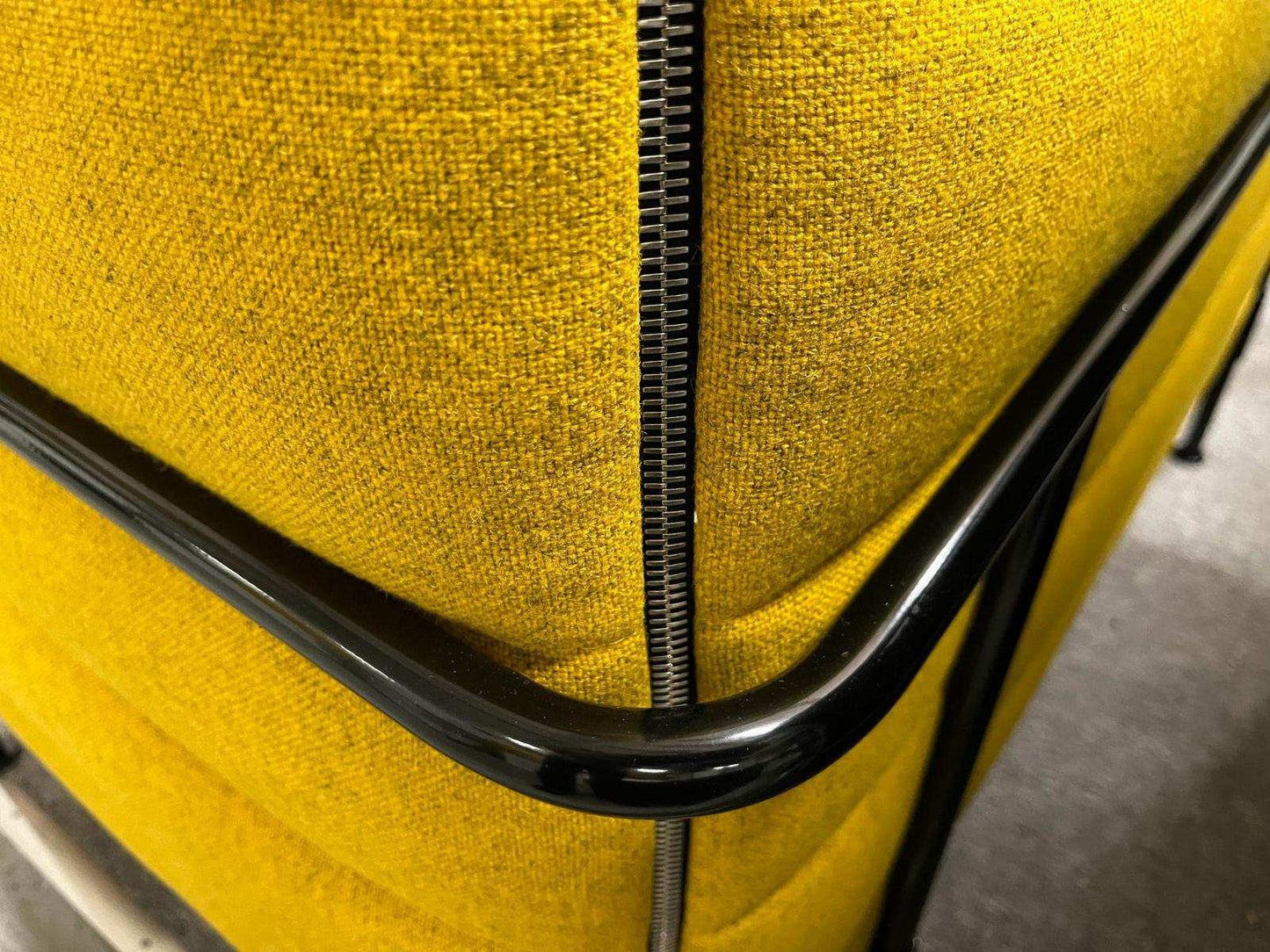 Close-up of yellow Vitra Alcove Highback Work chair fabric with black metal frame and zipper detail.