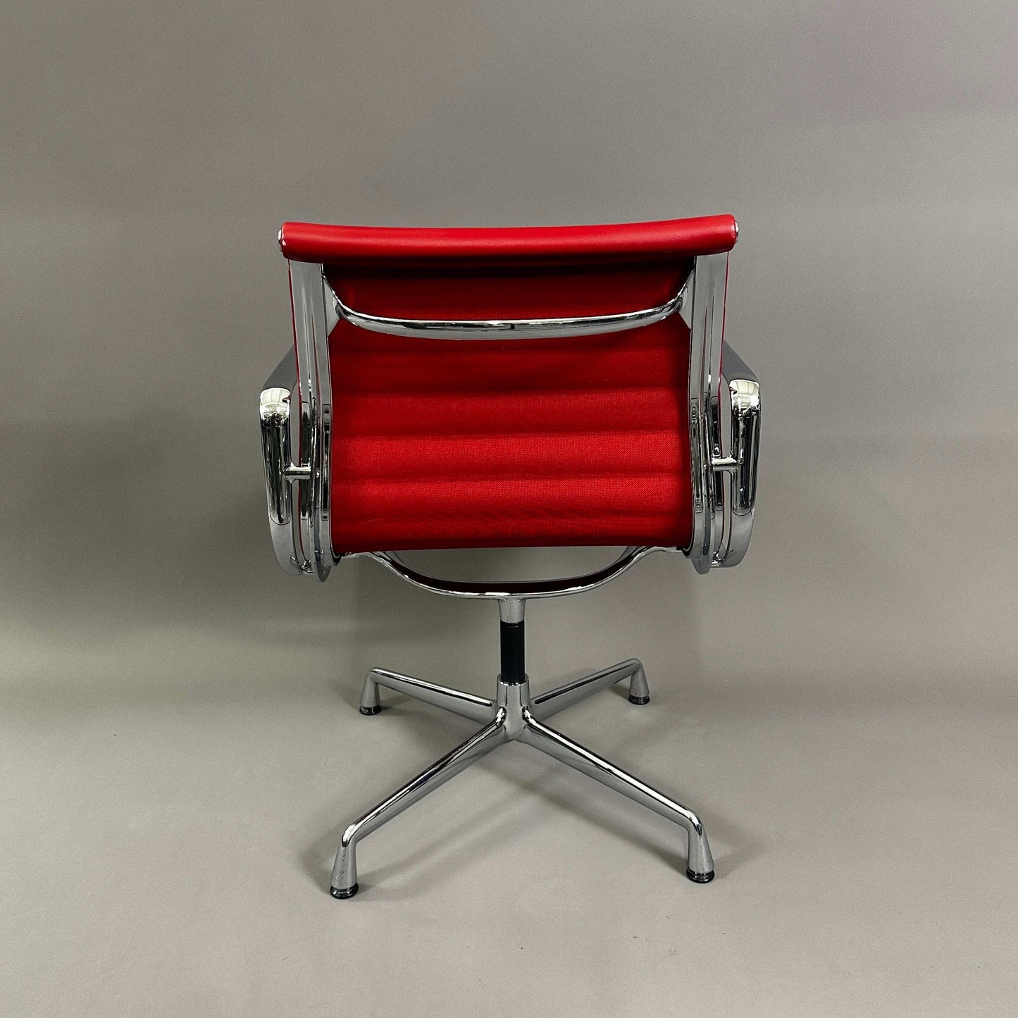 Vitra EA 108 swivel office chair with red leather upholstery and chrome frame, back view