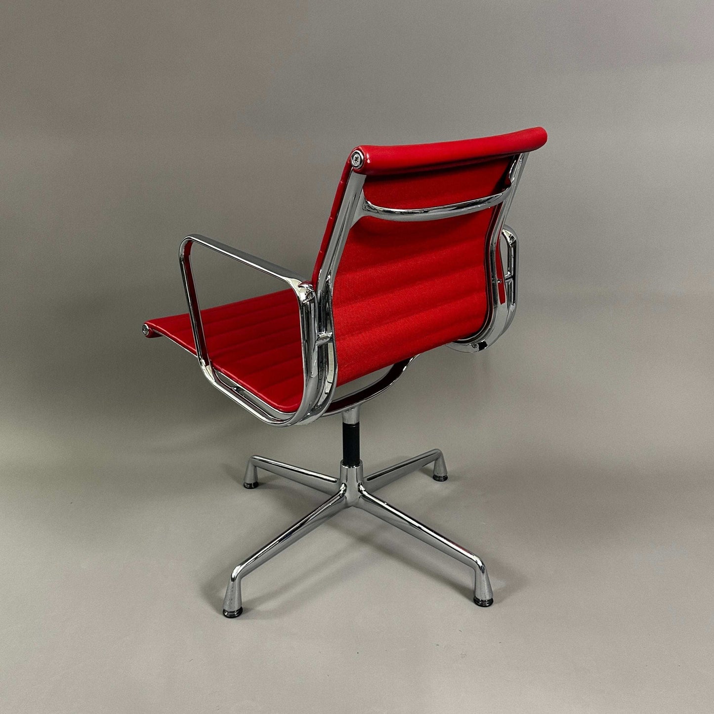 Vitra EA 108 swivel office chair with red leather upholstery and chrome frame, rear view