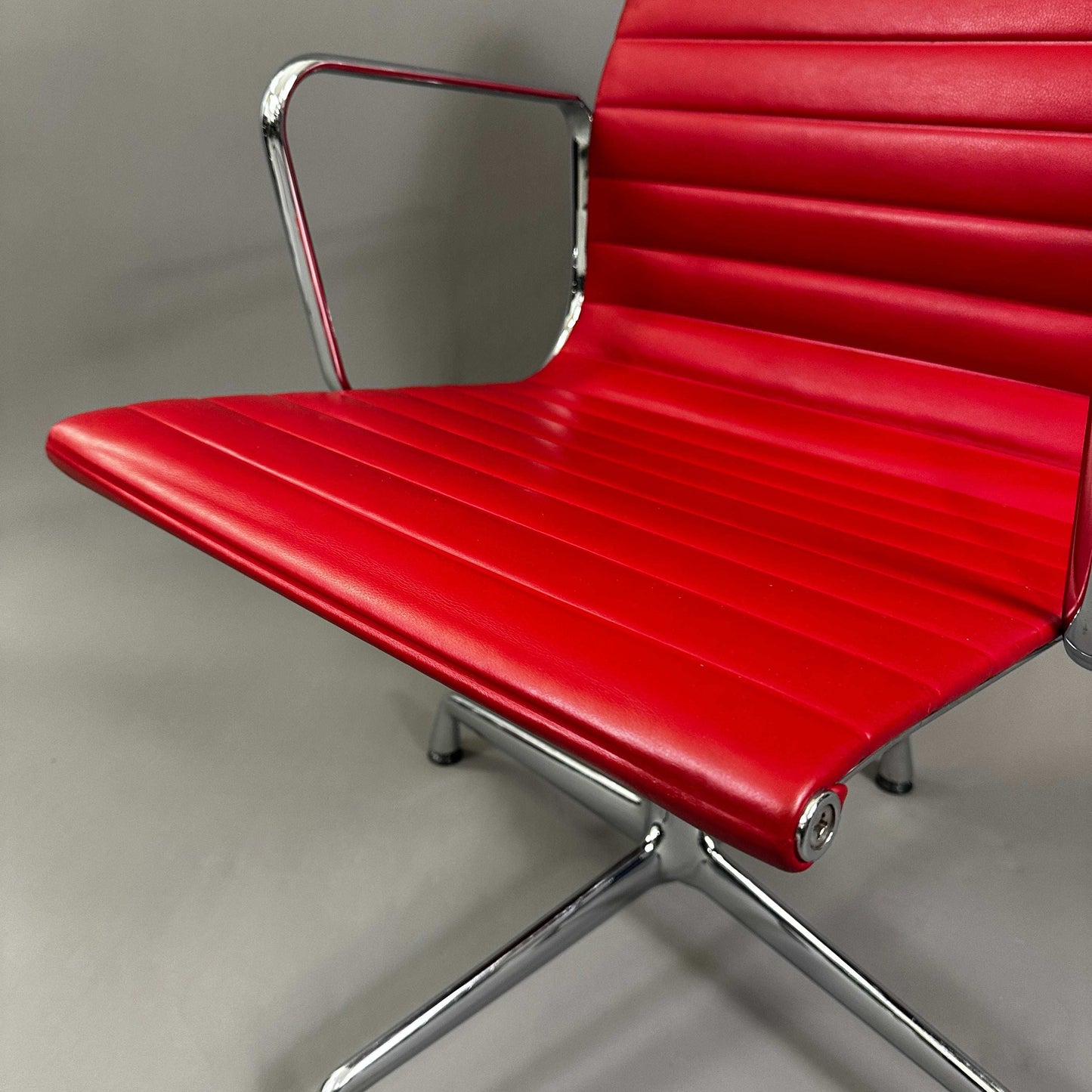 Vitra EA 108 swivel office chair with red leather seat and chrome frame