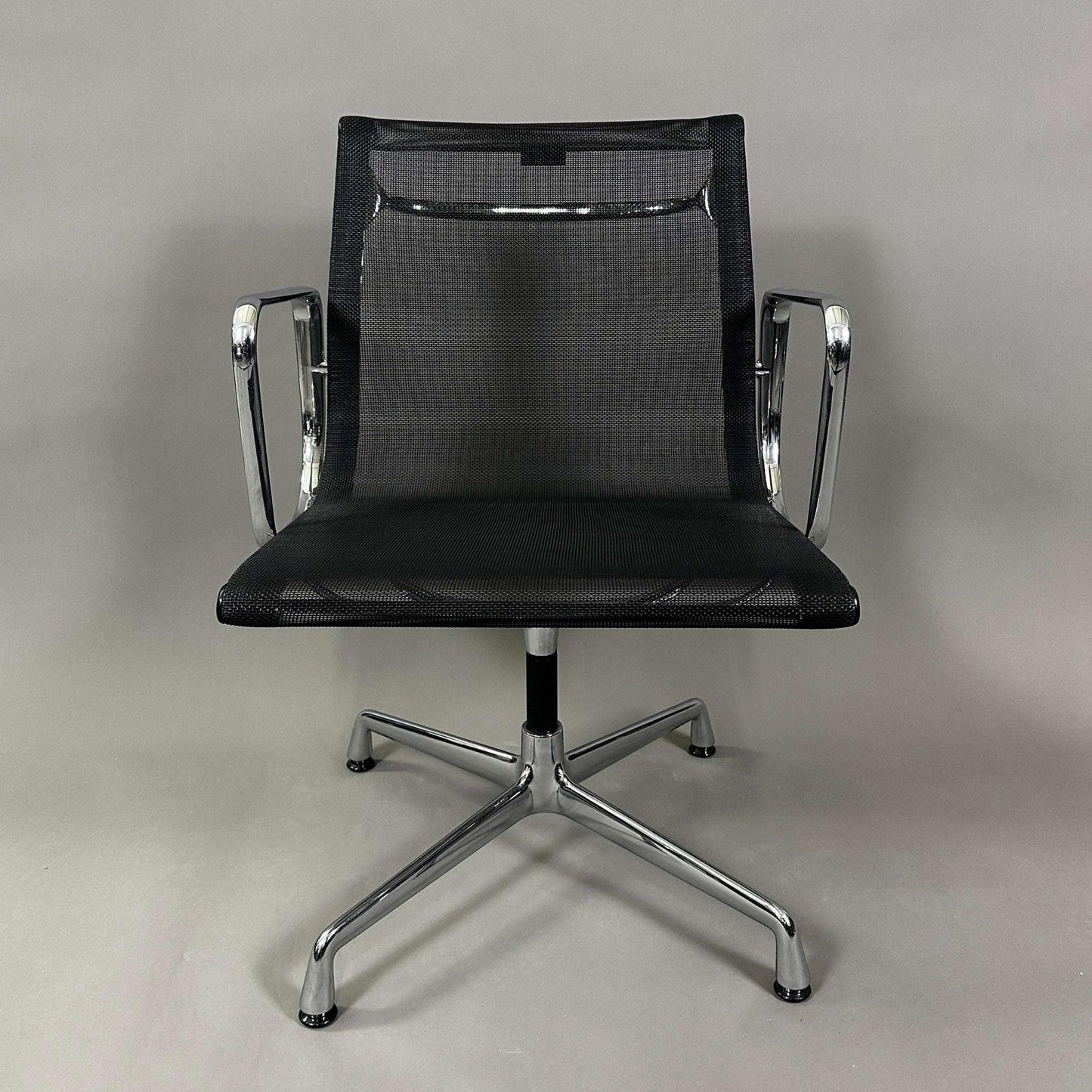 Vitra EA 108 black mesh swivel office chair with chrome frame and armrests