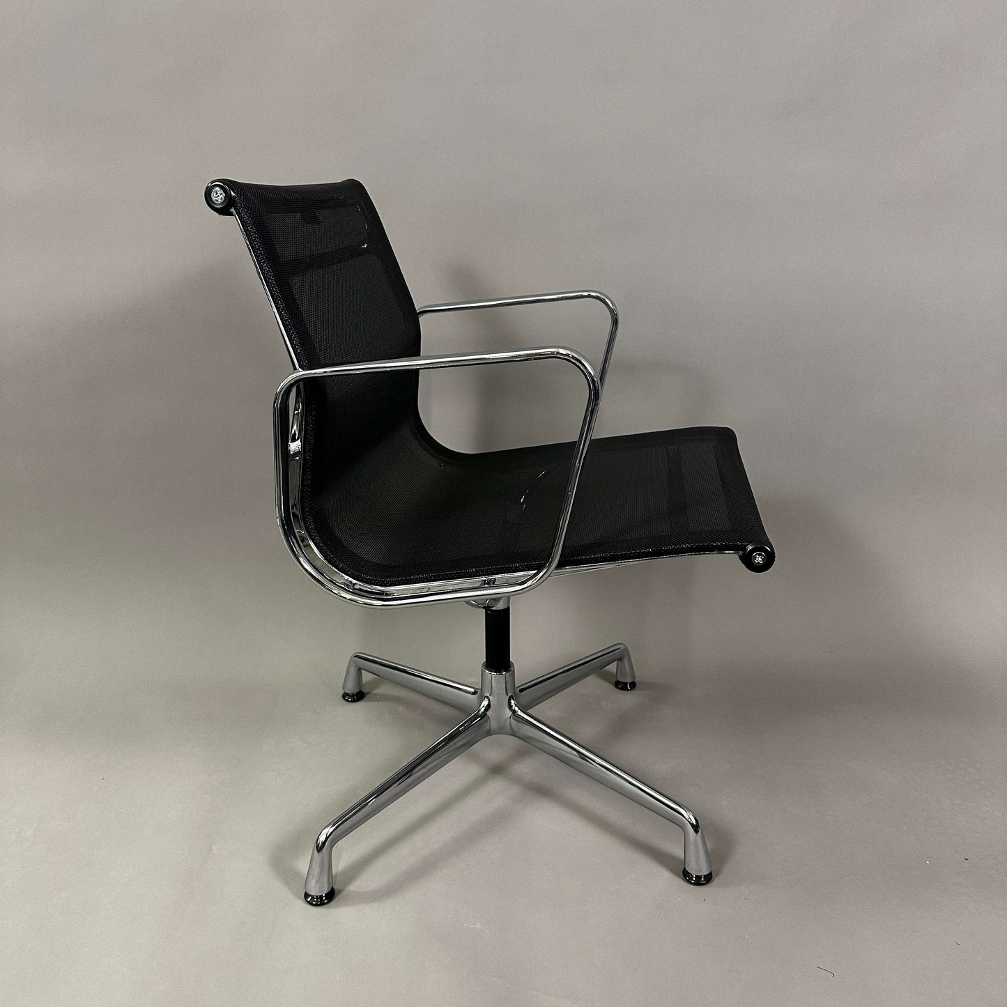 Vitra EA 108 office chair with black mesh seat and backrest, chrome frame, and swivel base