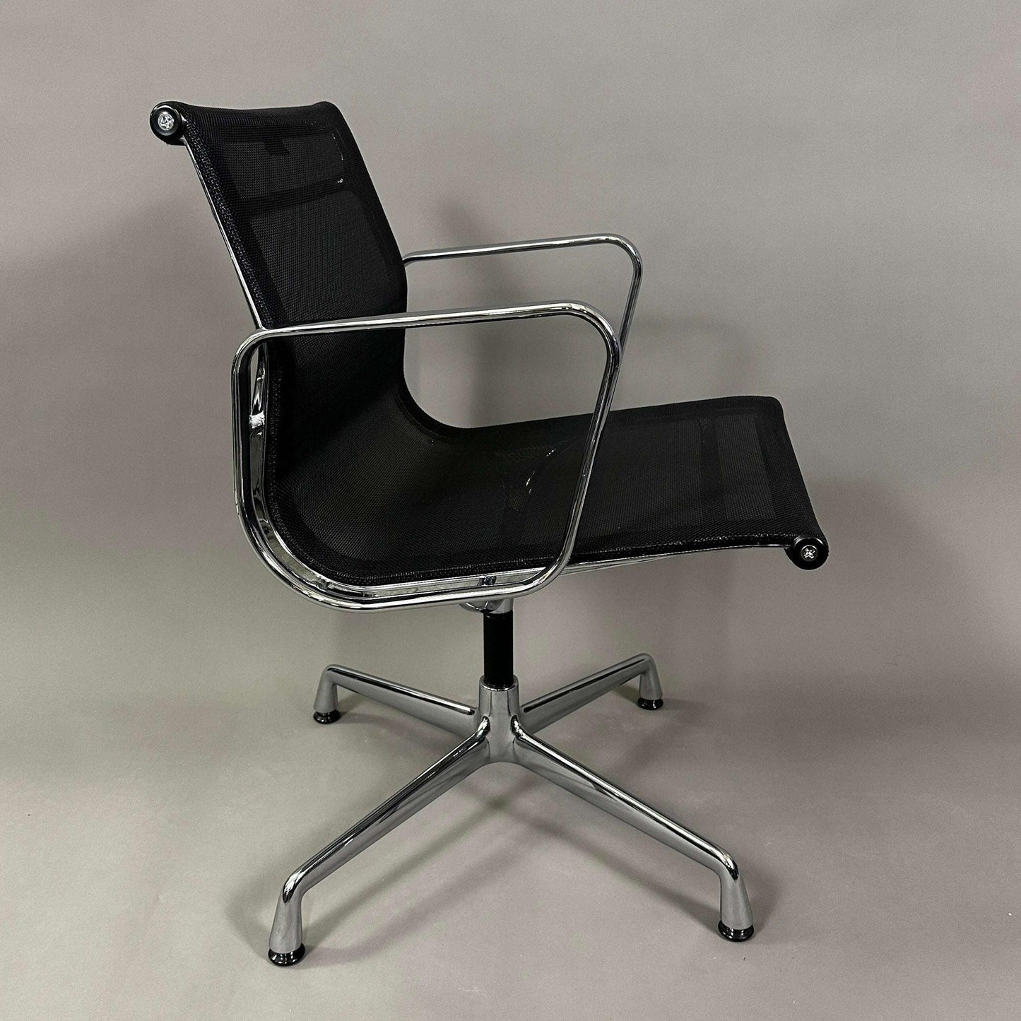 Vitra EA 108 office chair with black mesh seat and backrest, chrome frame, and swivel base