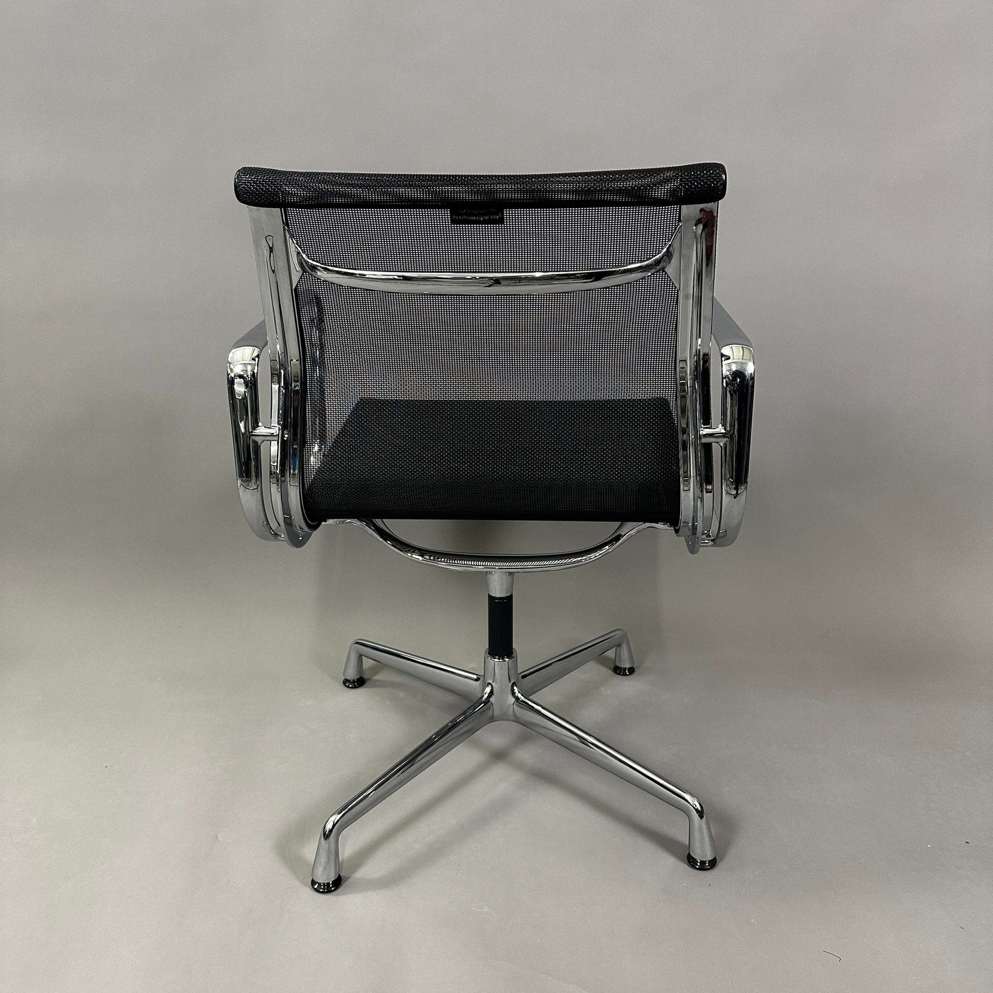 Vitra EA 108 swivel office chair with black mesh and chrome frame viewed from the back