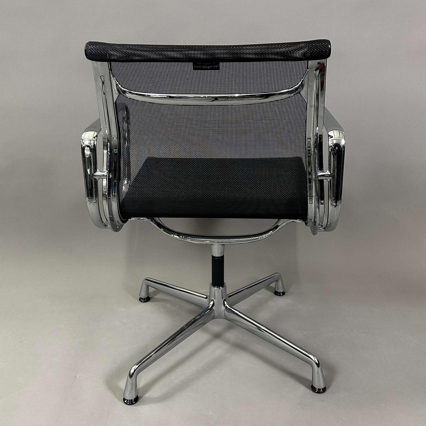 Vitra EA 108 swivel office chair with black mesh and chrome frame viewed from the back