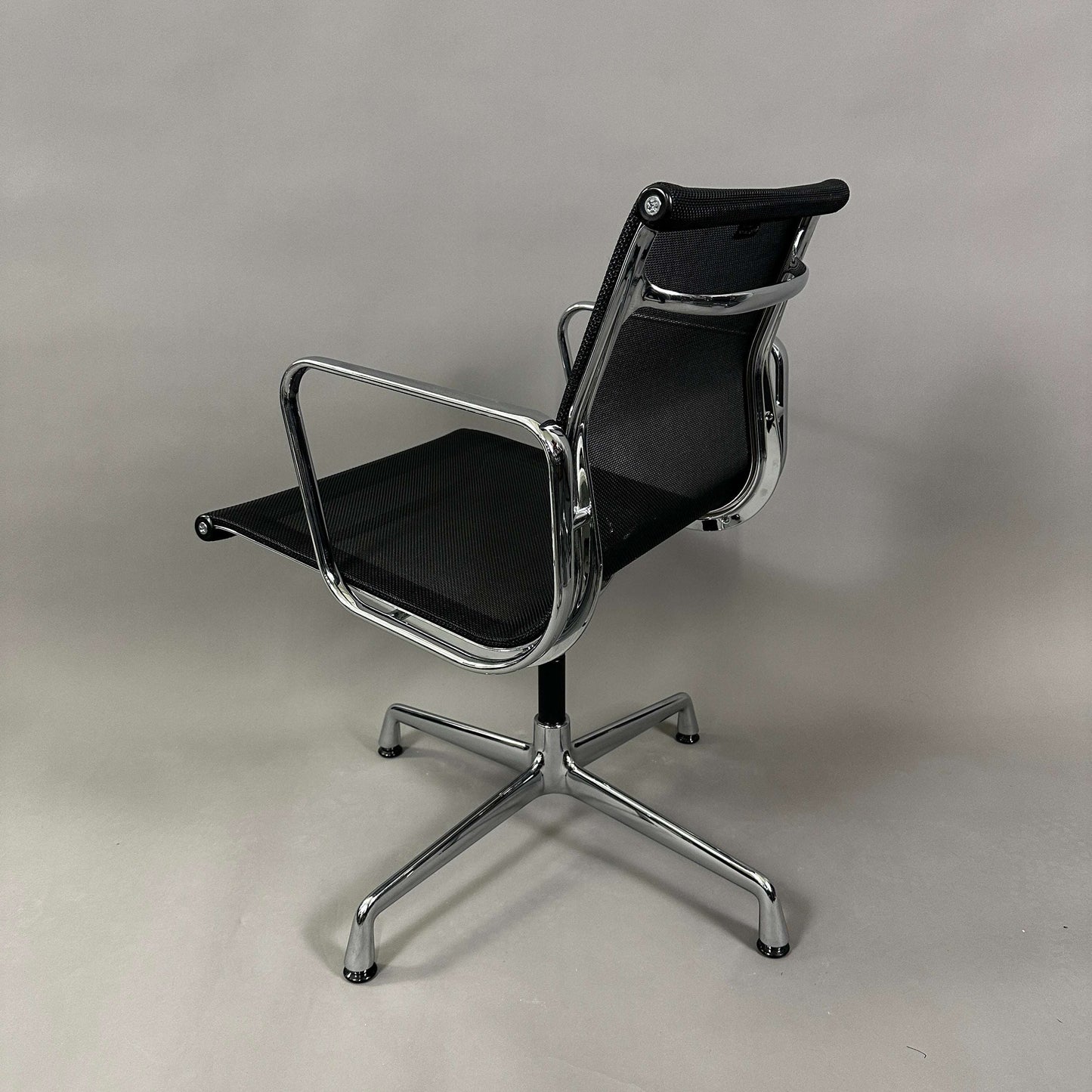 Vitra EA 108 black mesh swivel office chair with chrome frame and armrests