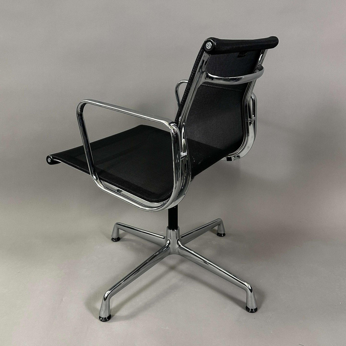 Vitra EA 108 black mesh swivel office chair with chrome frame and armrests