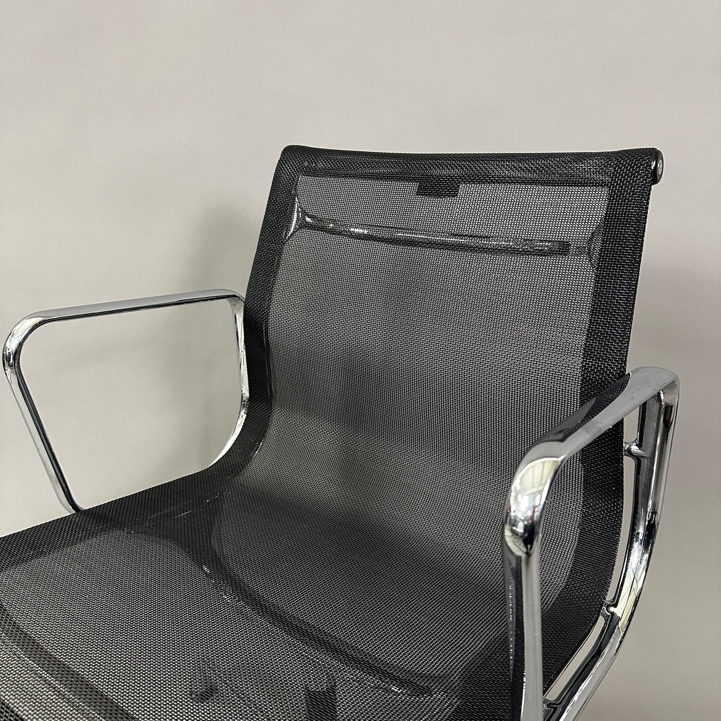 Vitra EA 108 black mesh swivel office chair with chrome frame and armrests