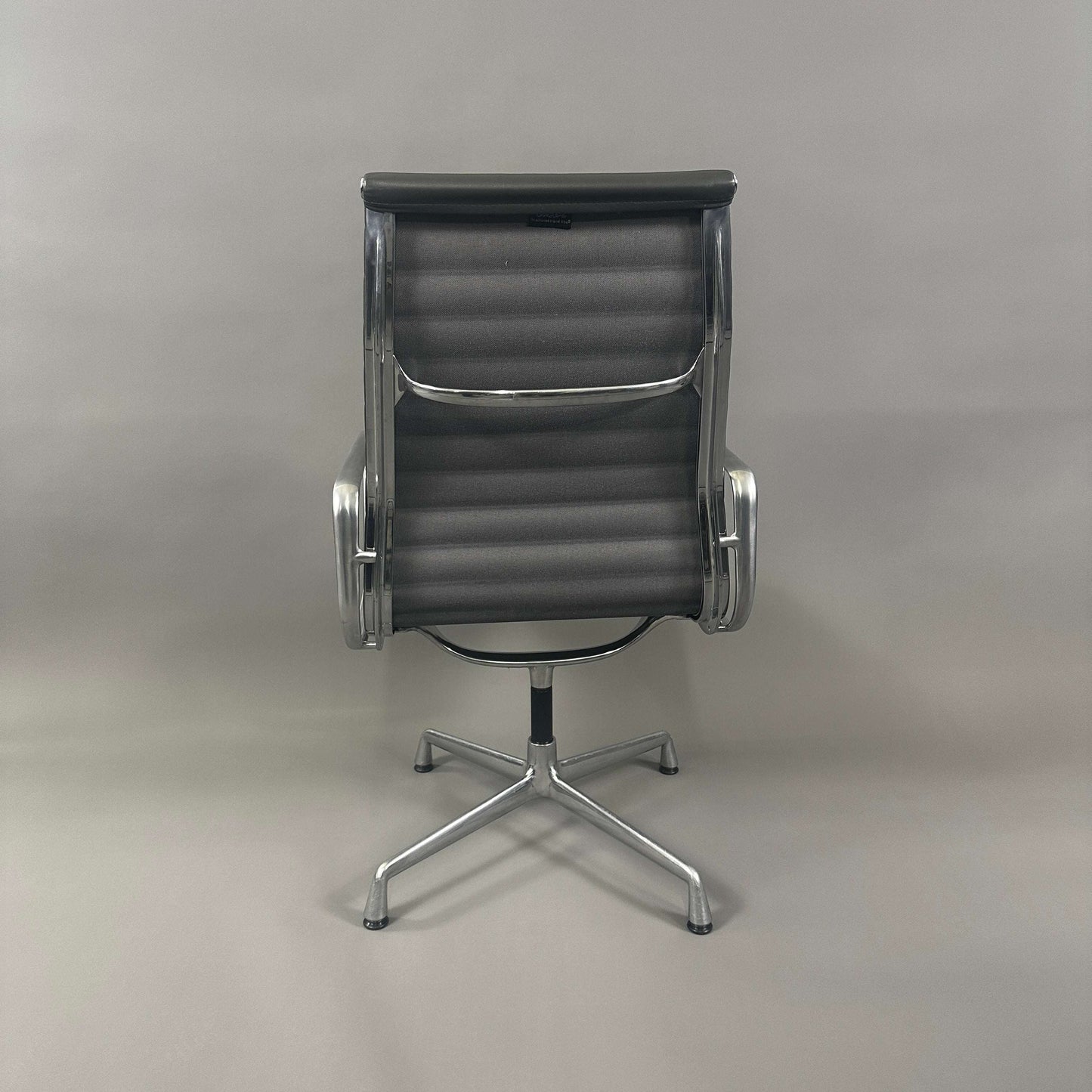 Vitra EA 112 Bürostuhl mit grauem Lederbezug und poliertem Aluminiumgestell von hinten fotografiert