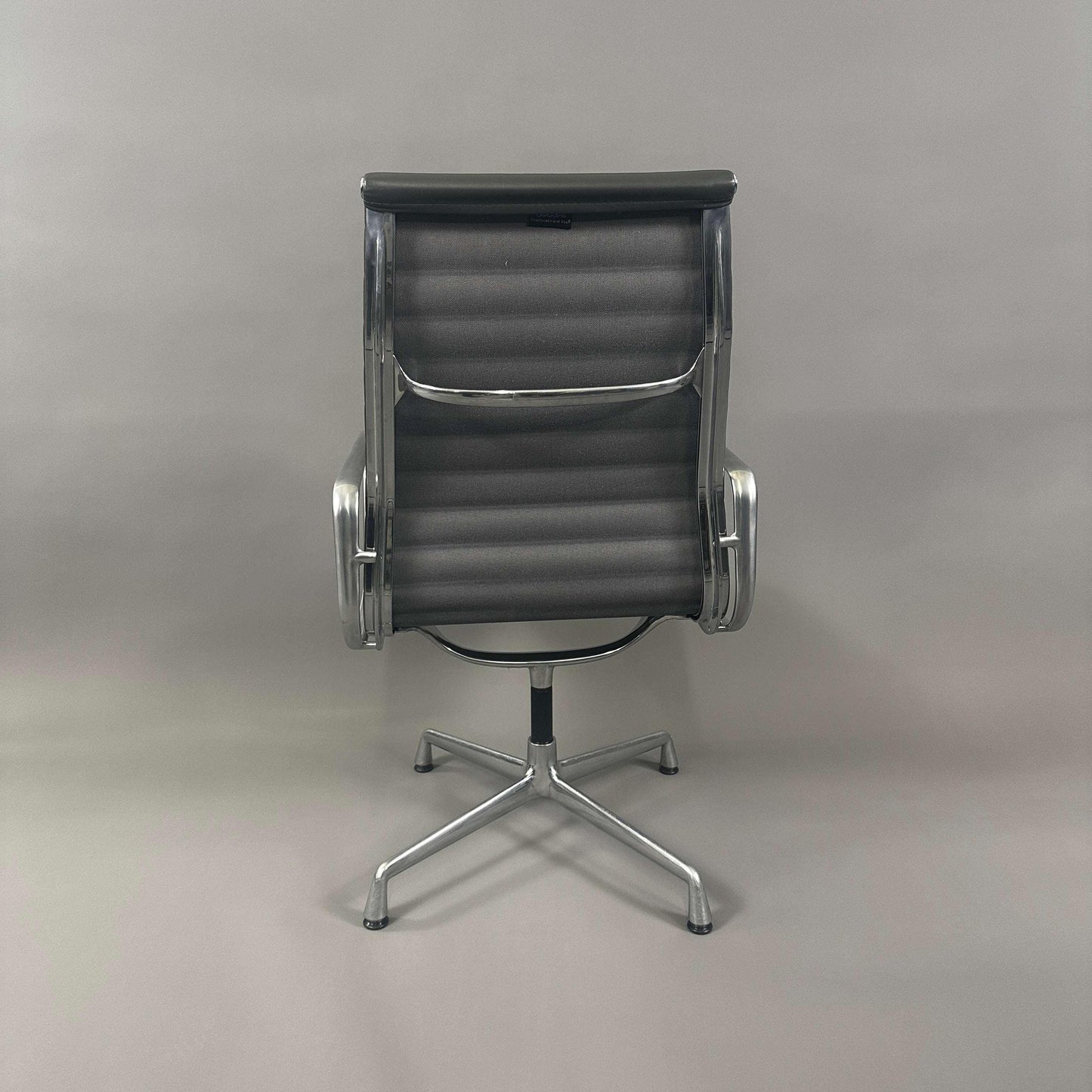 Vitra EA 112 Bürostuhl mit grauem Lederbezug und poliertem Aluminiumgestell von hinten fotografiert