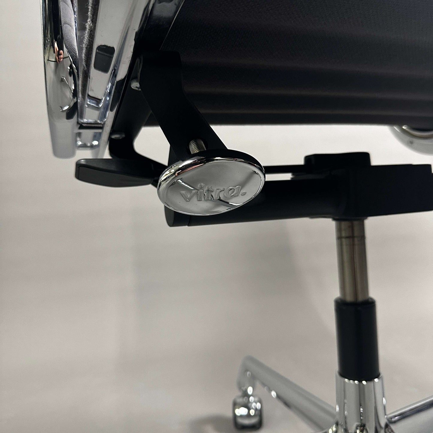 Nahaufnahme des verchromten Gestells und Verstellmechanismus des Vitra EA 117 Bürostuhls mit grauem Hopsak-Bezug