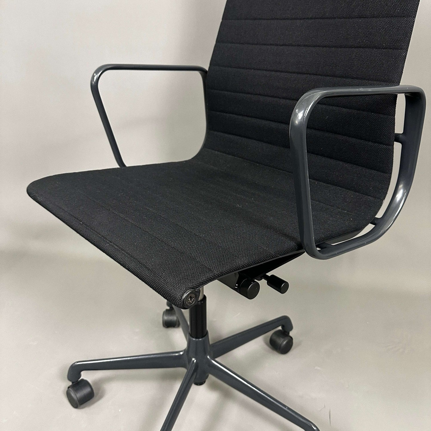 Black Vitra EA 119 Hopsak office chair with adjustable height and tilt, black metal frame, and five-star aluminum base on casters
