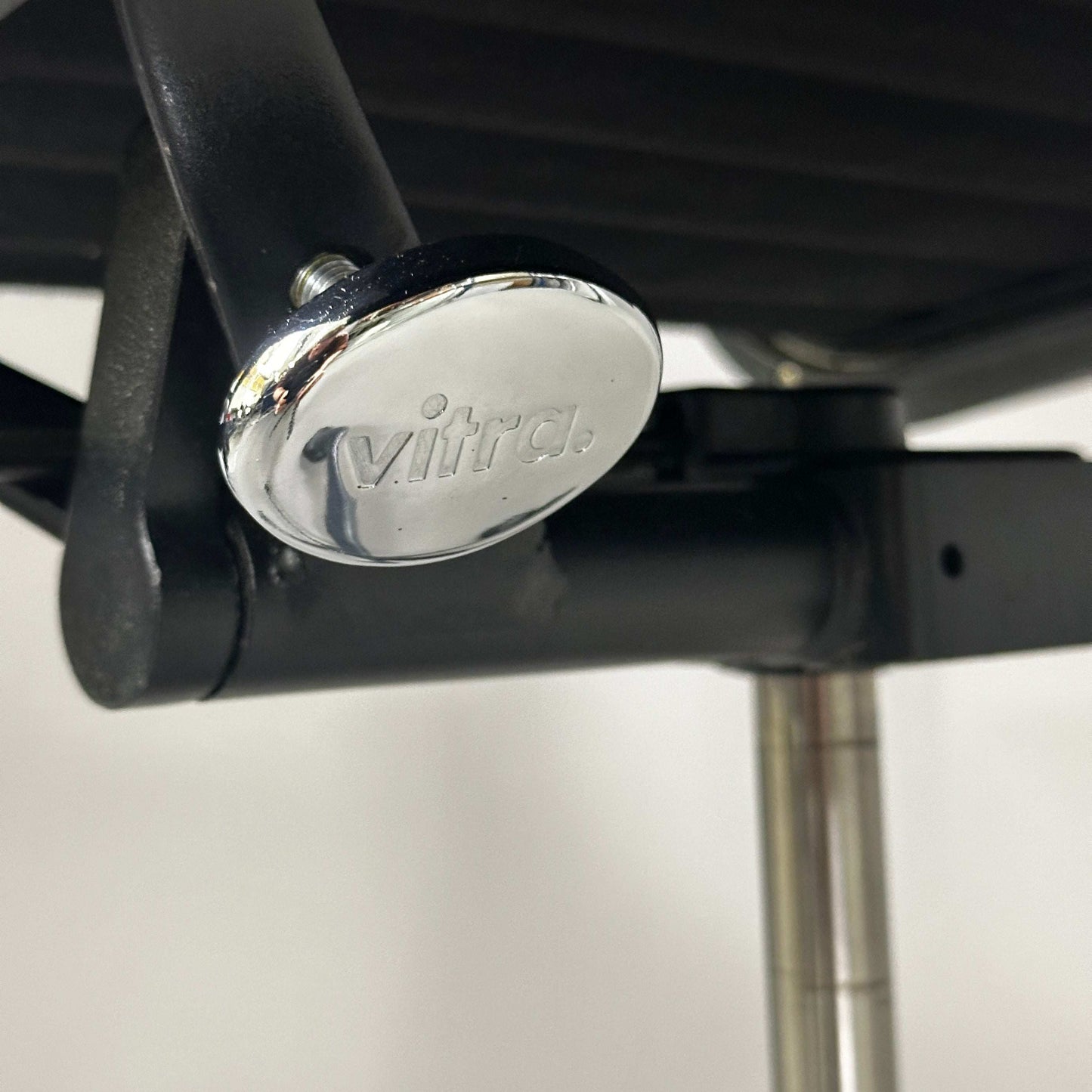 Close-up of Vitra EA 119 Hopsak black chair's adjustable mechanism with black frame and chrome detail