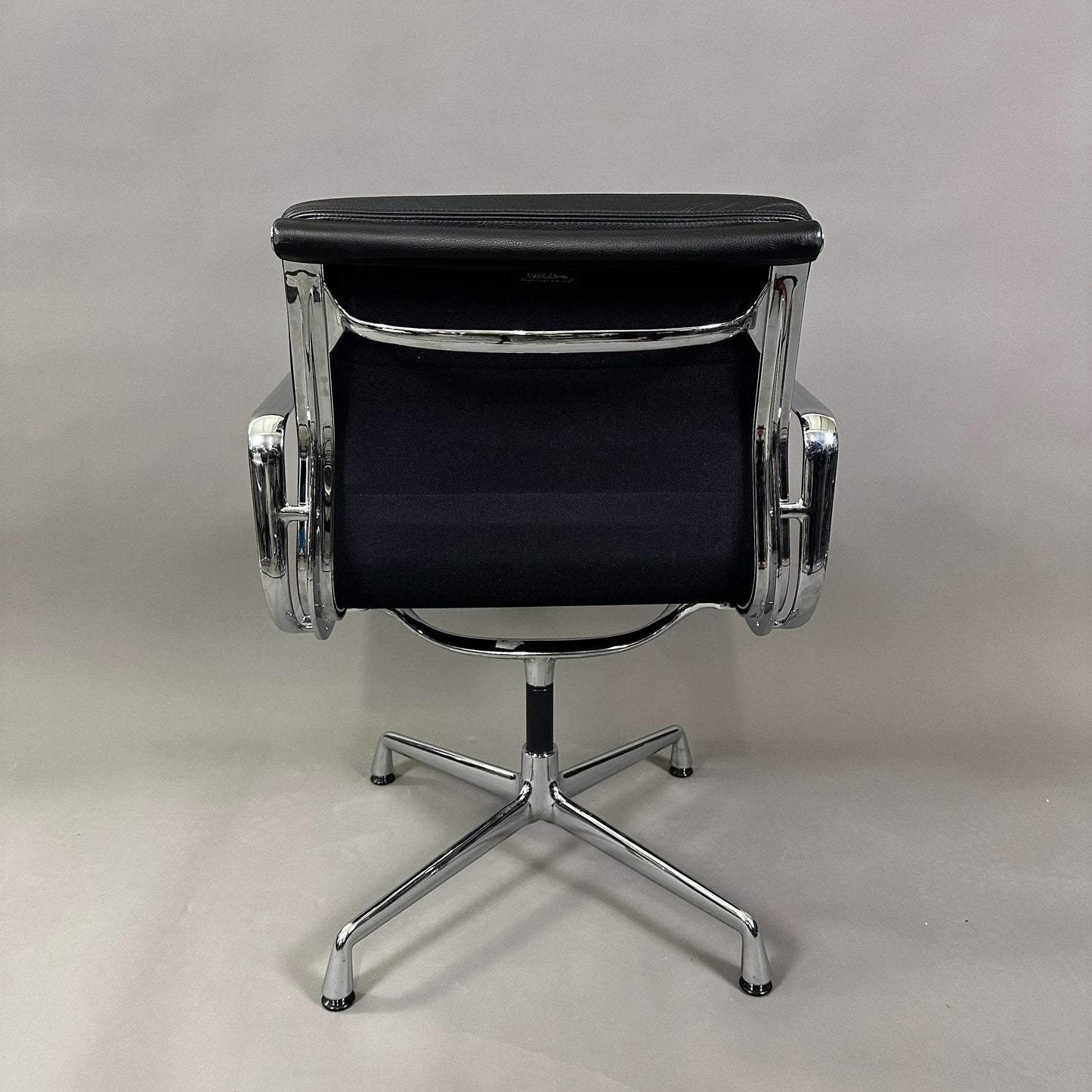 Back view of Vitra EA 208 swivel chair with black soft padded leather seat and chrome frame