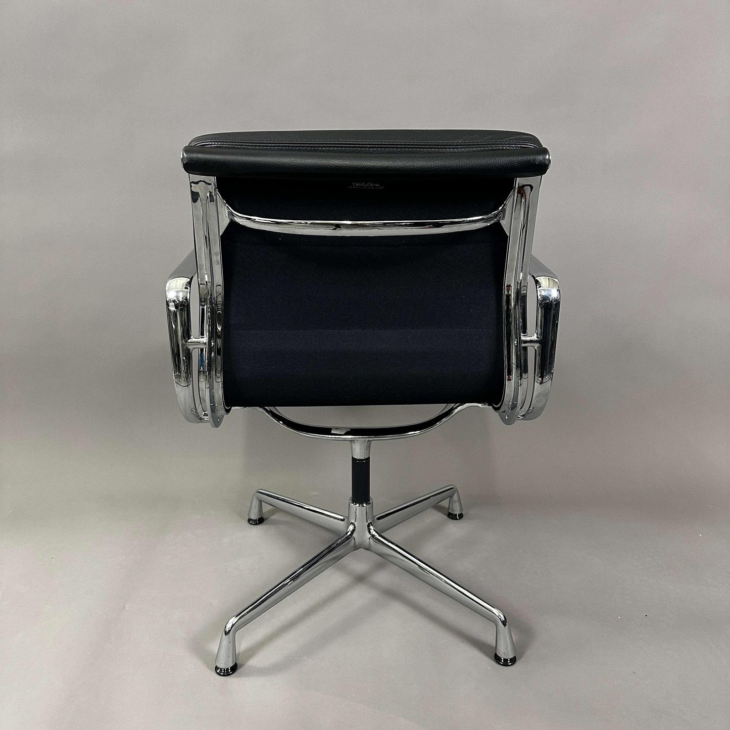 Back view of Vitra EA 208 swivel chair with black soft padded leather seat and chrome frame